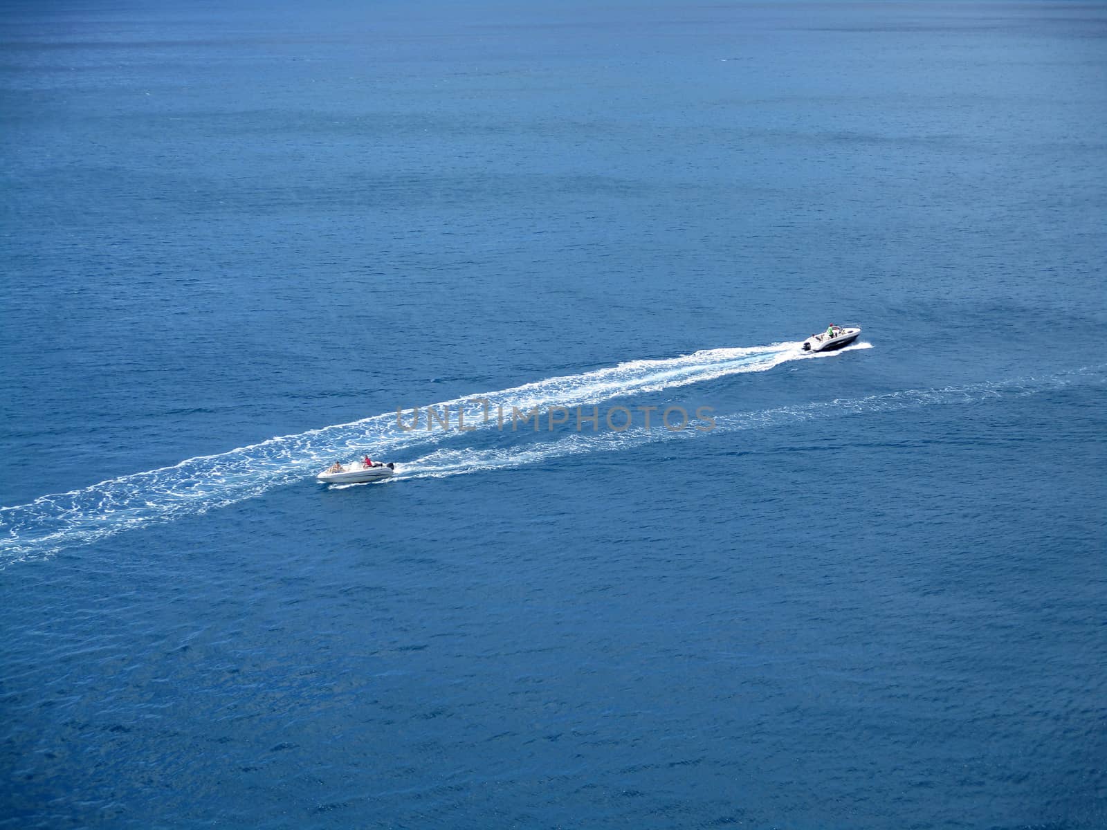 speed boats that leave a white strip in the blue sea