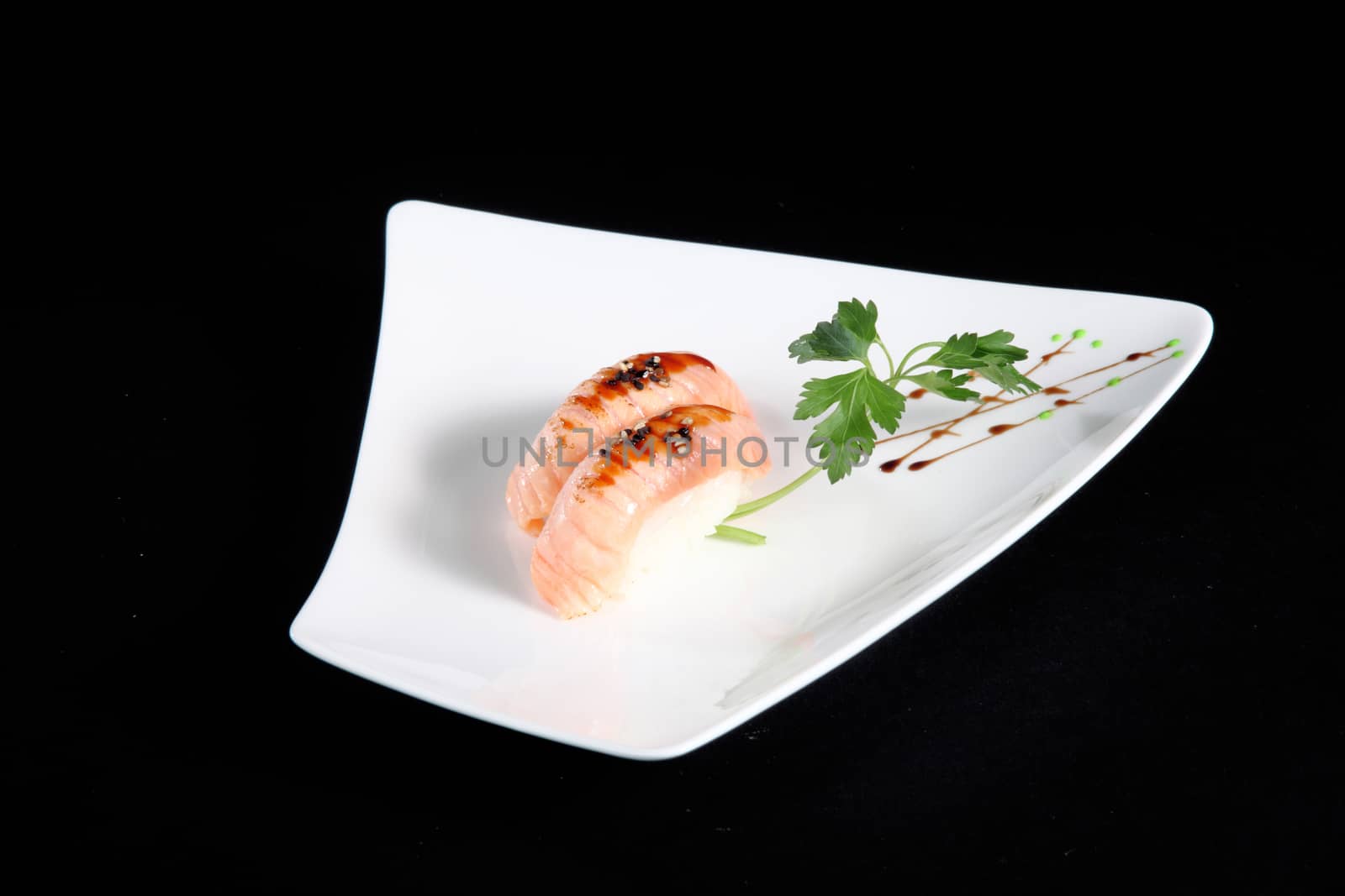 portion of sushi with vegetables on white plate, black background