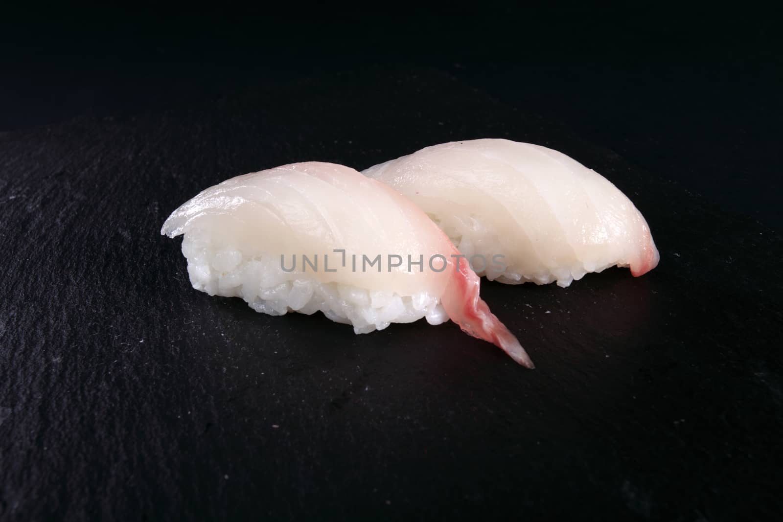 two sushi on black plate, black background