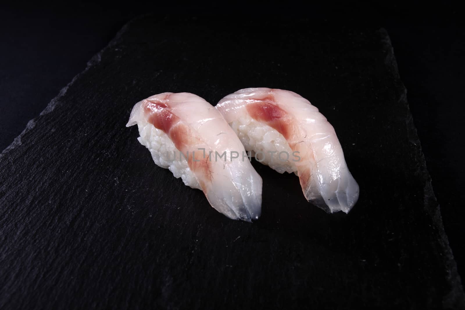 mixed sushi on white plate, black background