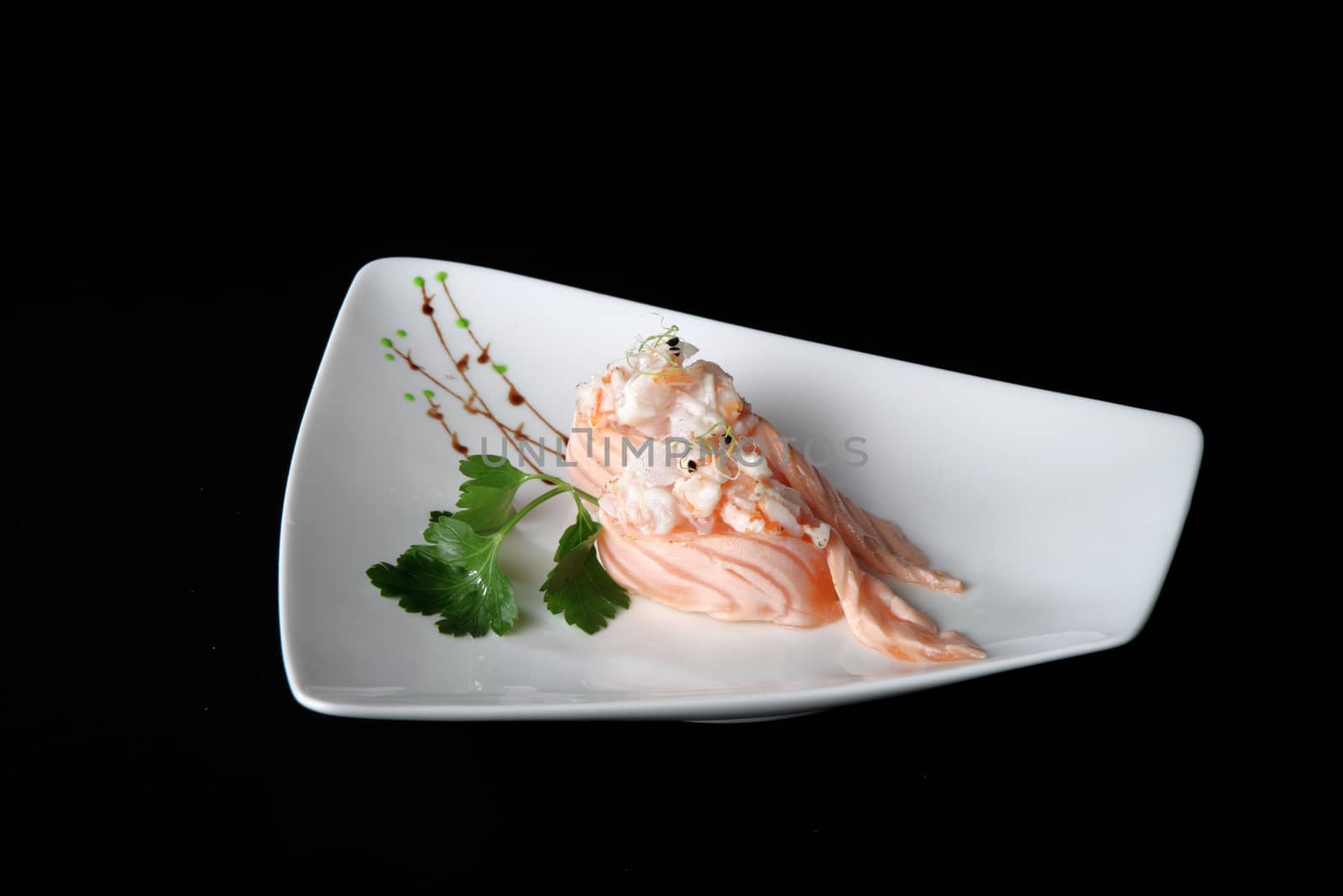 portion of sushi with vegetables on white plate, black background