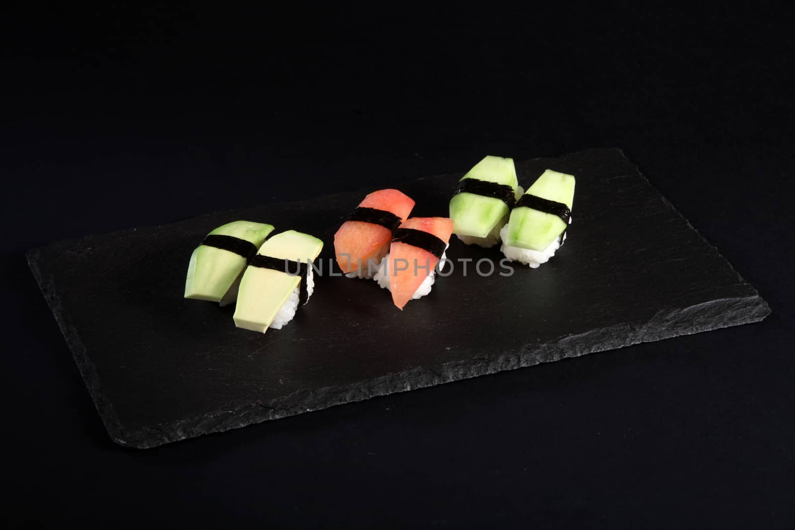 Vegetable sushi on flat slate, black background