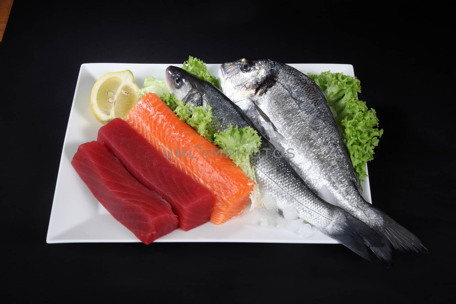 plate of mixed fish on a black background