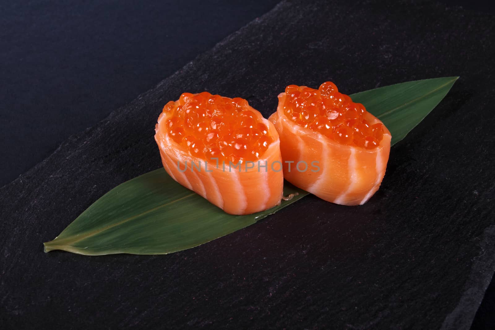 rolls with fish eggs on leaf green, black background