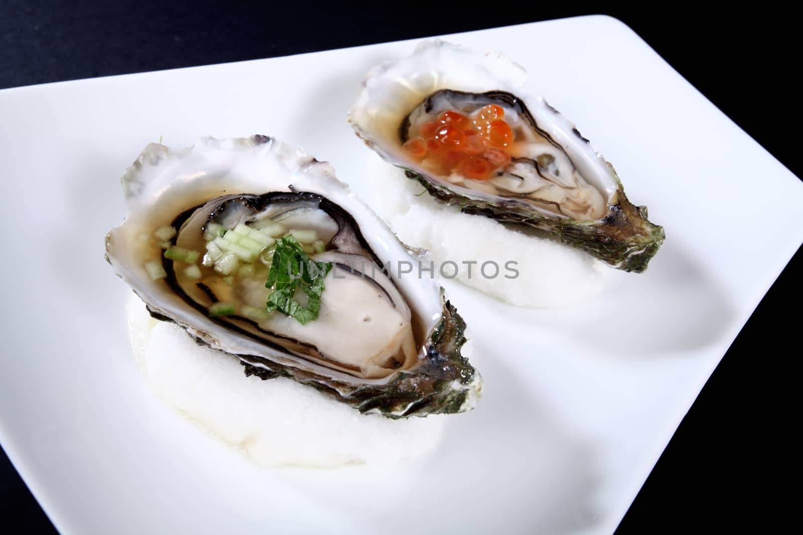 white plate with two oysters on a black background