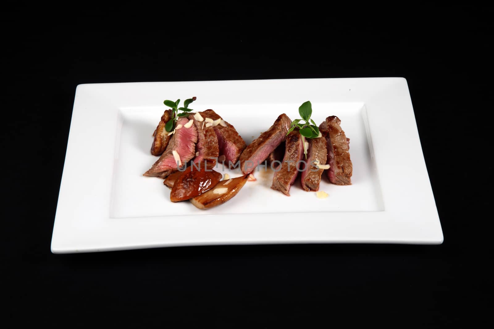 beef with mushrooms in white plate on a black background