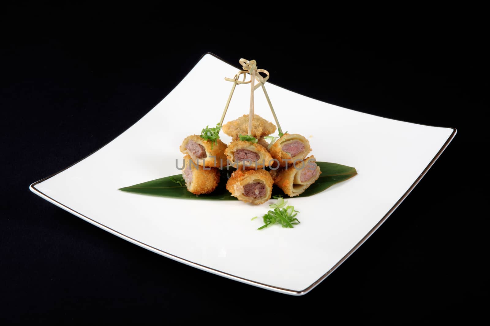 breaded fish with vegetables in white plate on black background