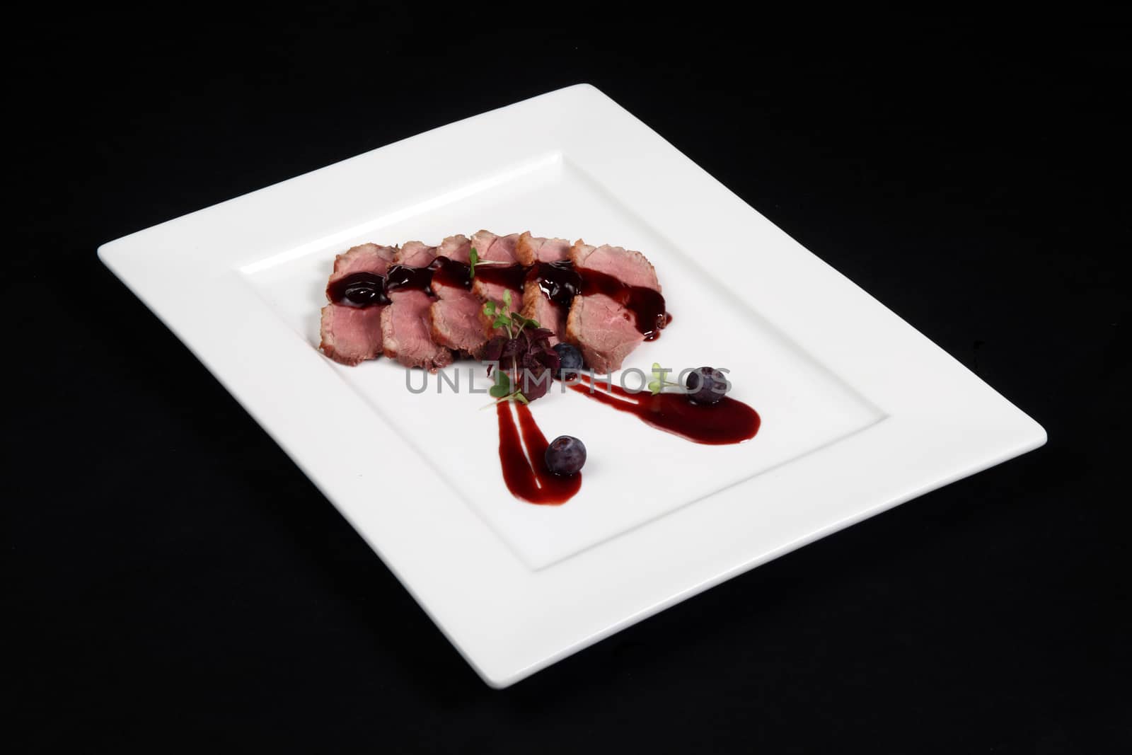 duck meat with cranberry cream in white plate on a black background