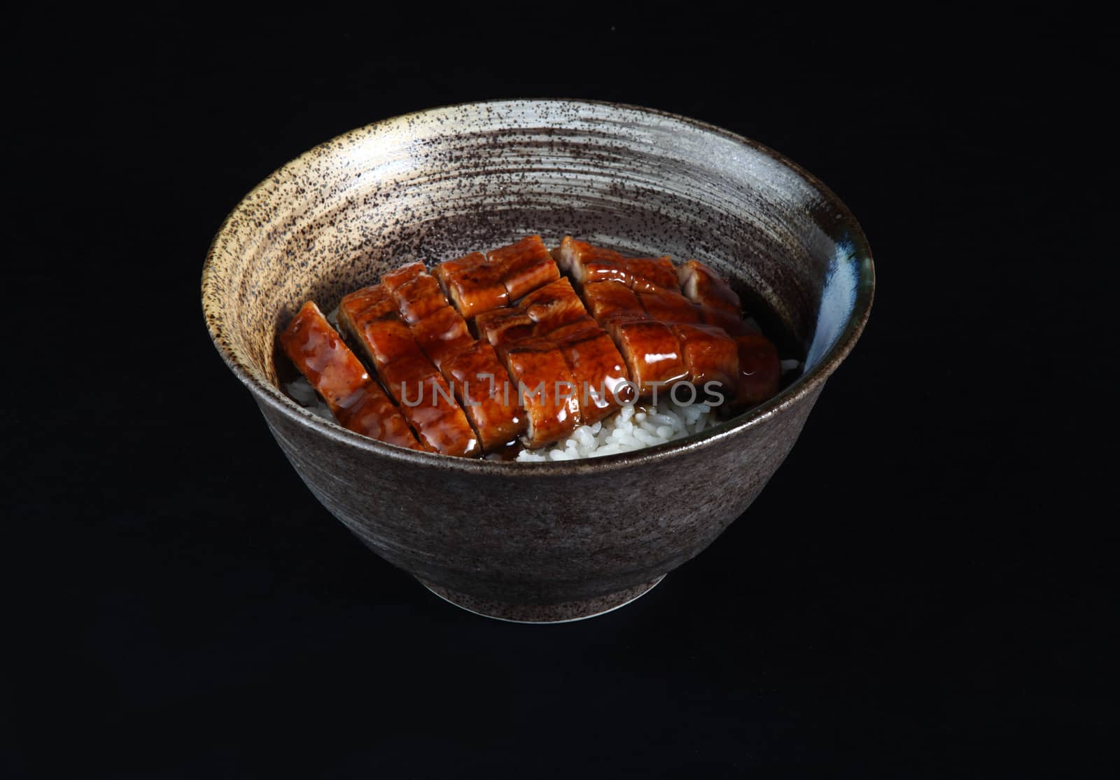 eel meat with rice in bowl on a black background