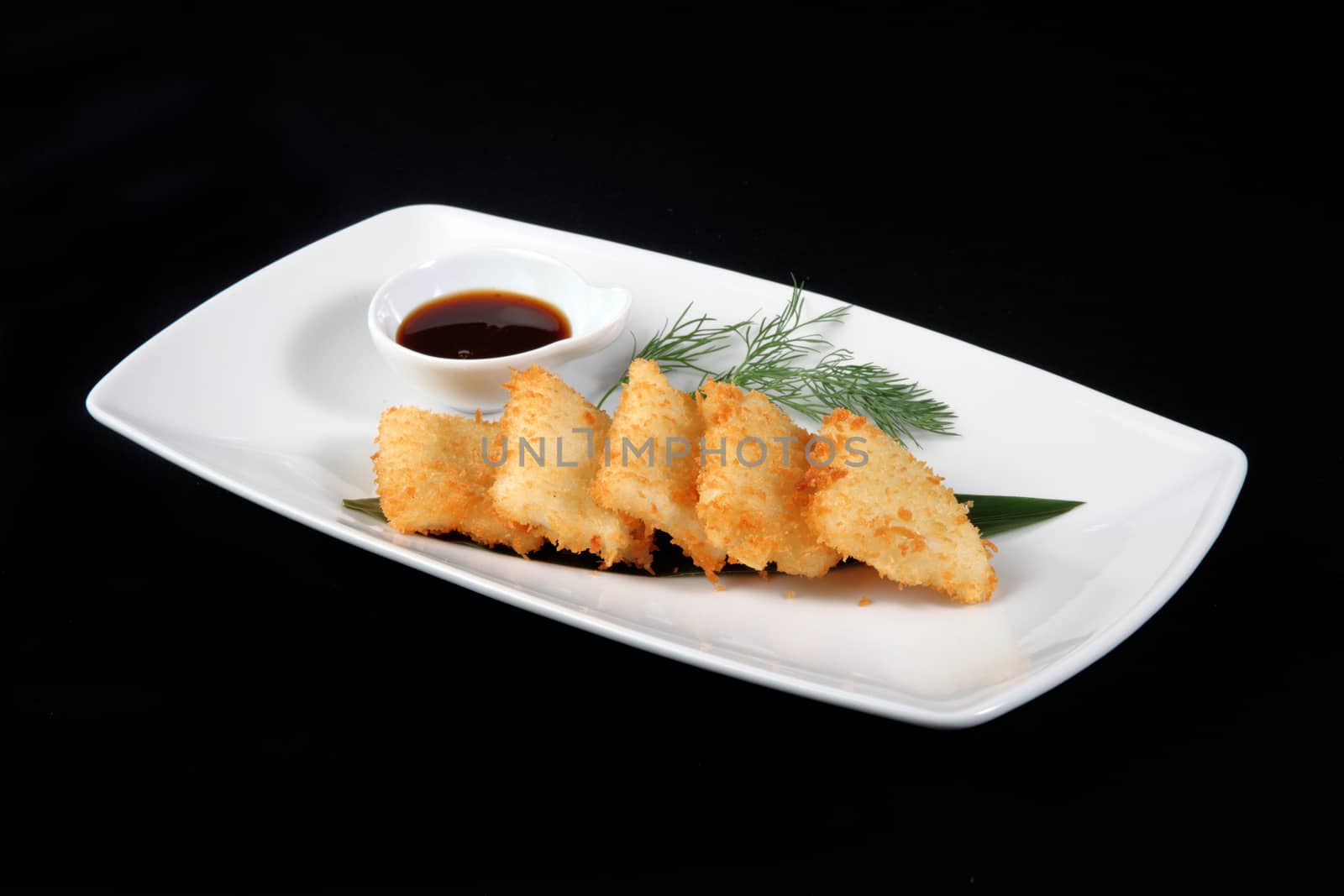 breaded squid in white plate on a black background