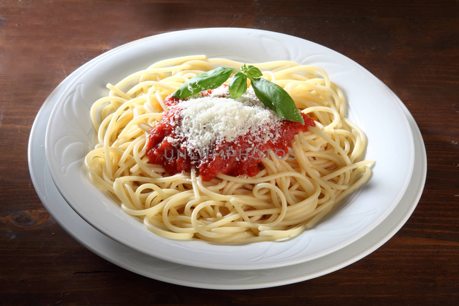 Italian dish of spaghetti with tomato and basil on a wooden table