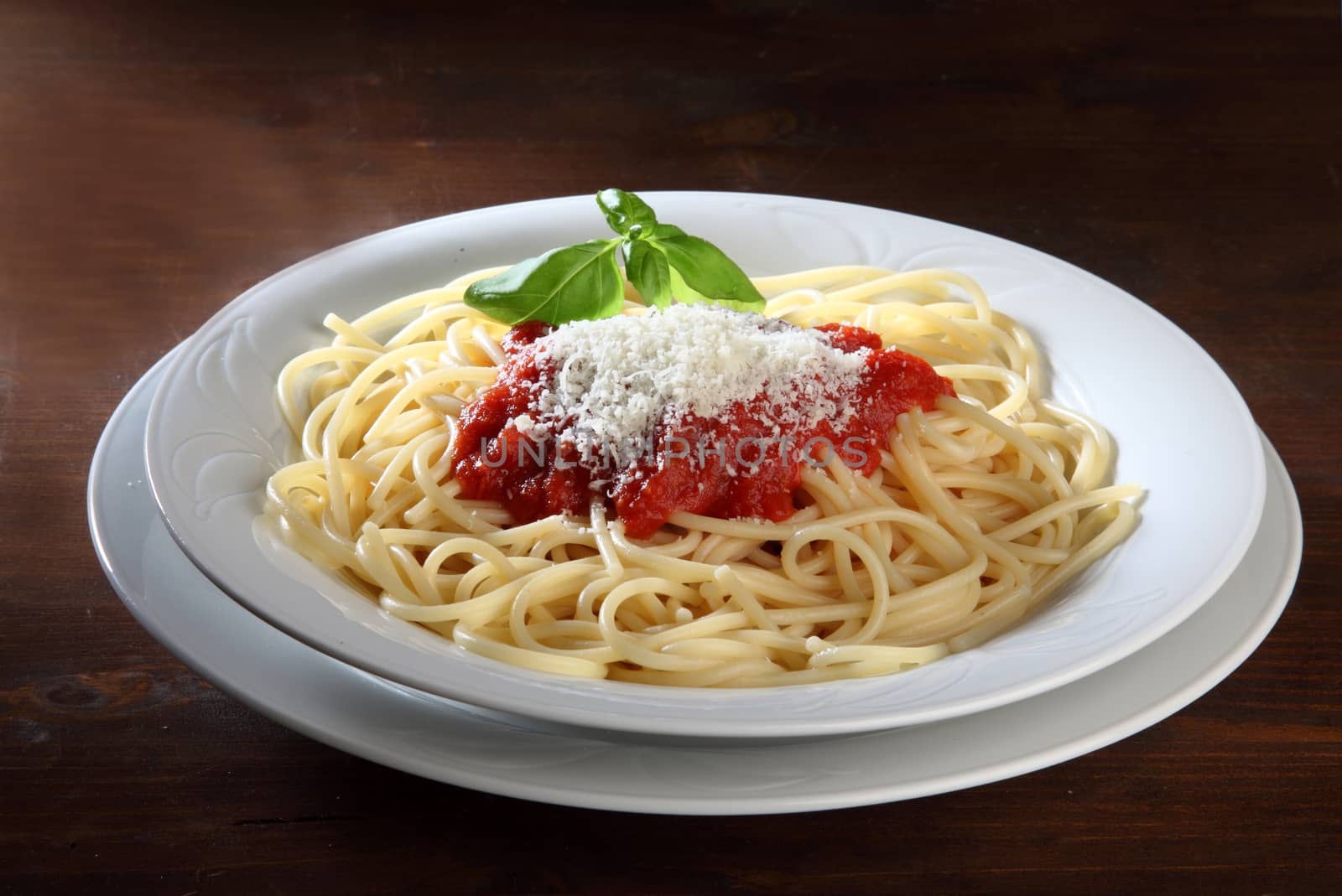 Italian dish of spaghetti with tomato and basil on a wooden table