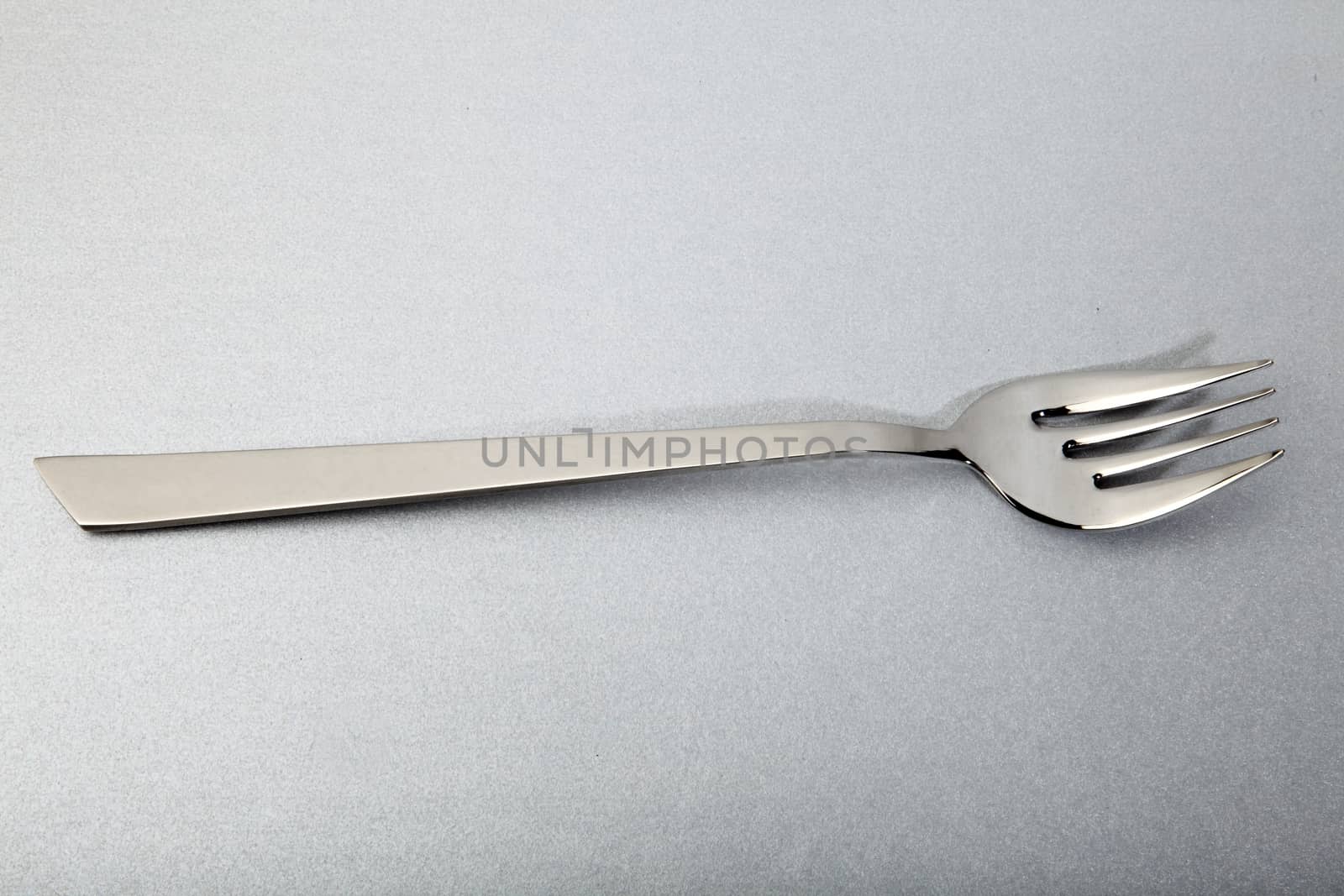 elegant steel fork for fish, on a silver background