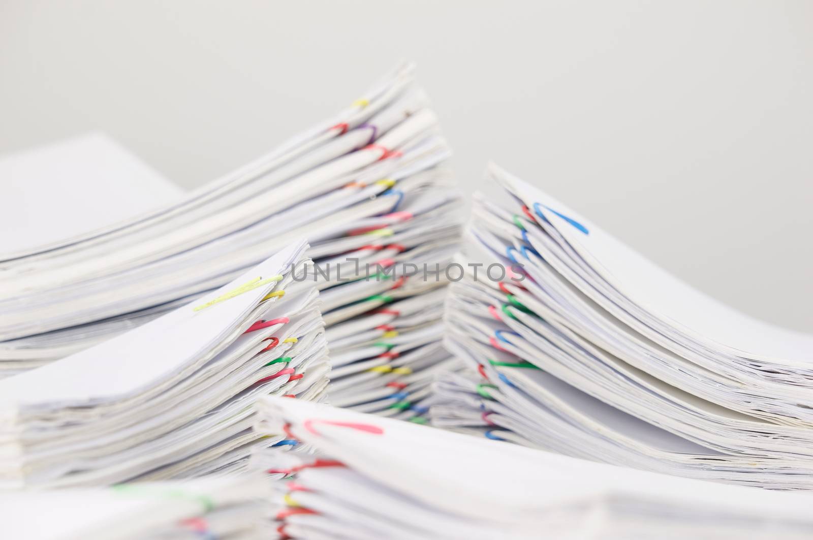 Pile overload document of receipt and report with colorful paperclip have blur pile paperwork foreground and background on white table.