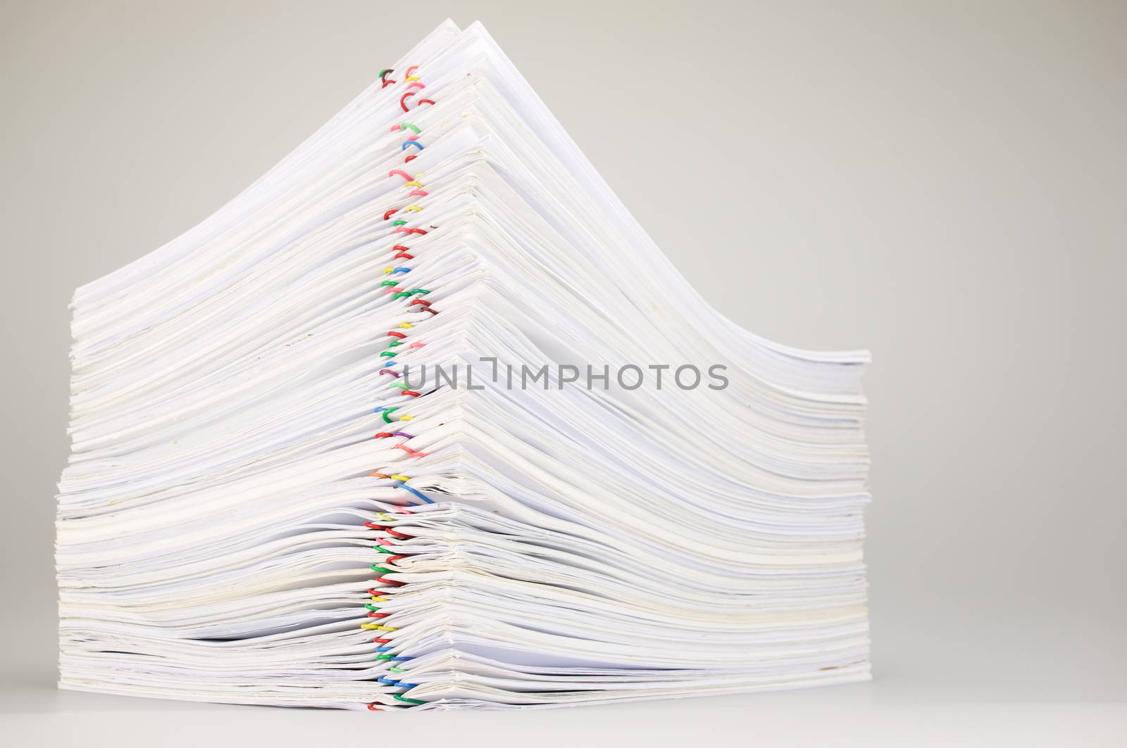 Pile overload paperwork of receipt and report with colorful paperclip on white table.