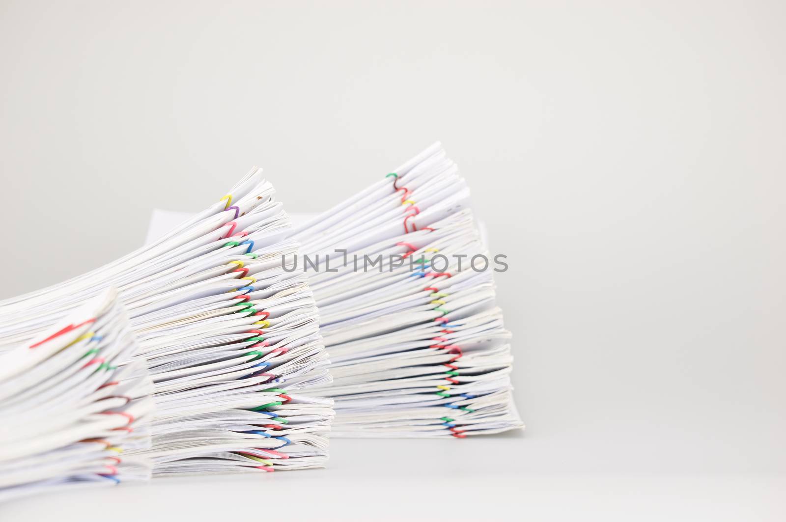 Step pile overload paperwork of receipt and report with colorful paperclip have blur pile document foreground and background on white table.