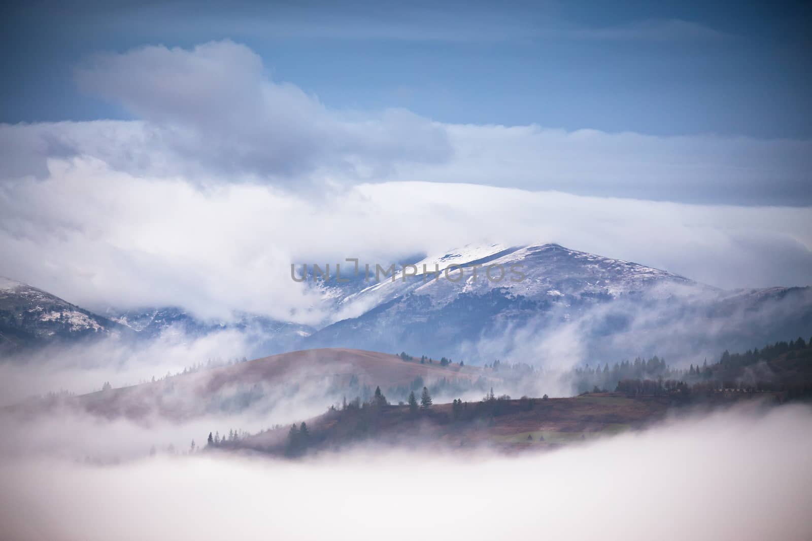 Autumn, November foggy and snowy morning in Carpathian mountain panorama. 