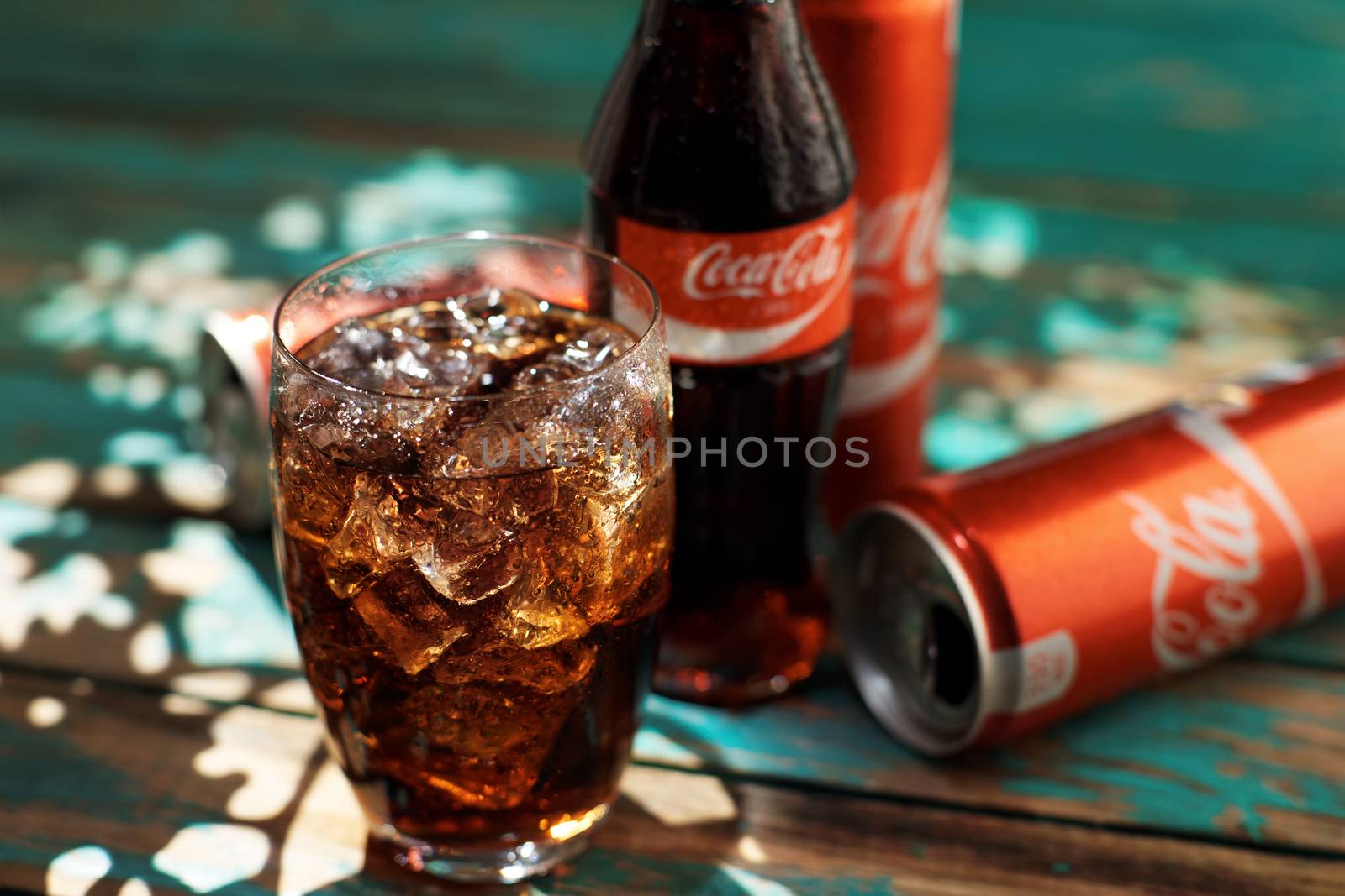 MINSK, BELARUS-AUGUST 25, 2016. Can and a glass of iced Coca-Cola on a wooden table by vmytra