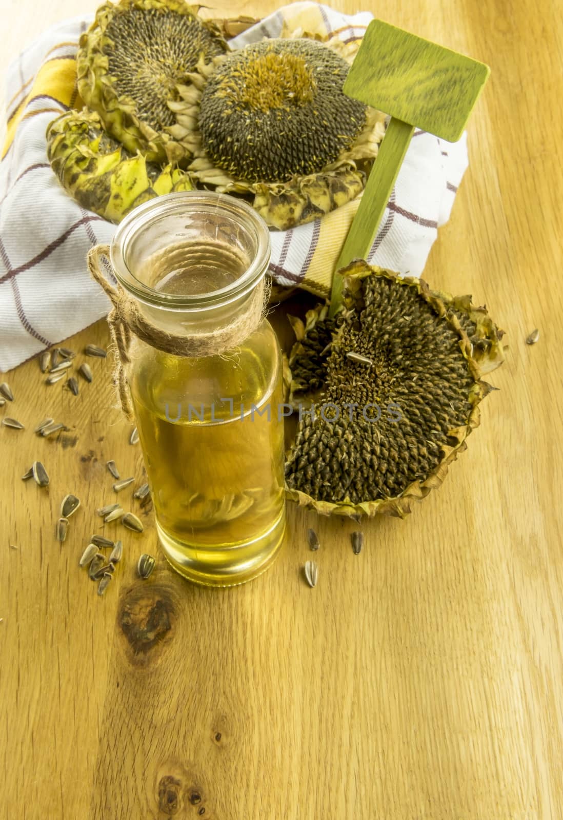 Glass bottle with sunflower oil and a basket with sunflower plants on a wooden table