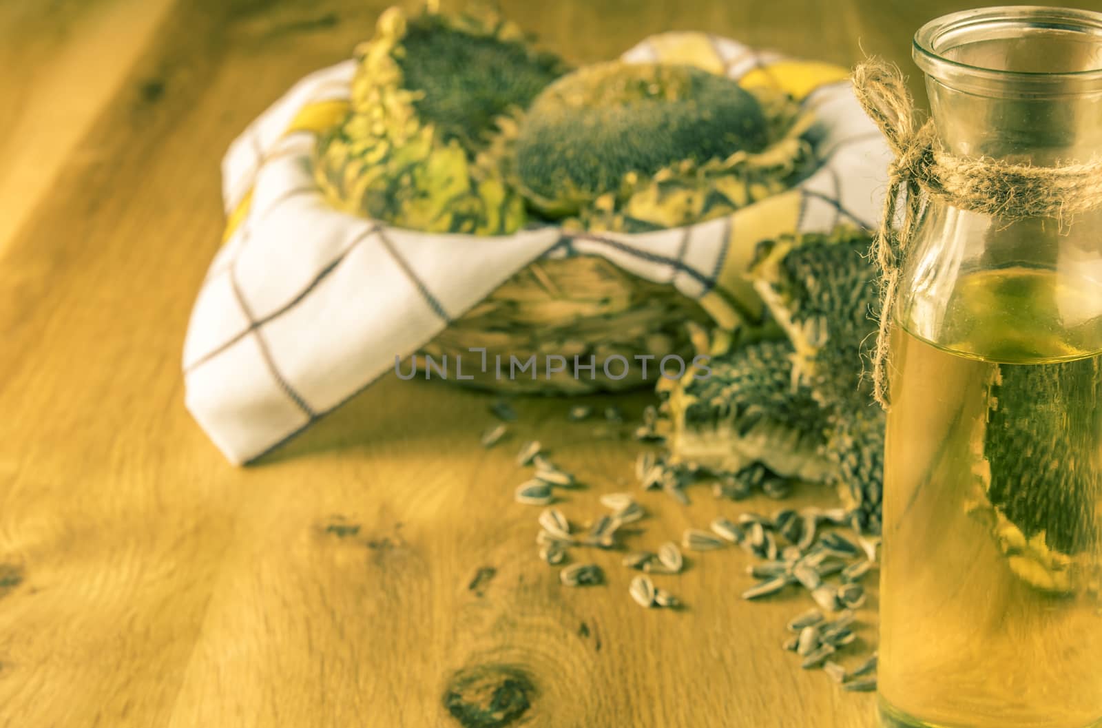 Rustic image with sunflower oil and a wooden basket full with sunflower plants and seeds