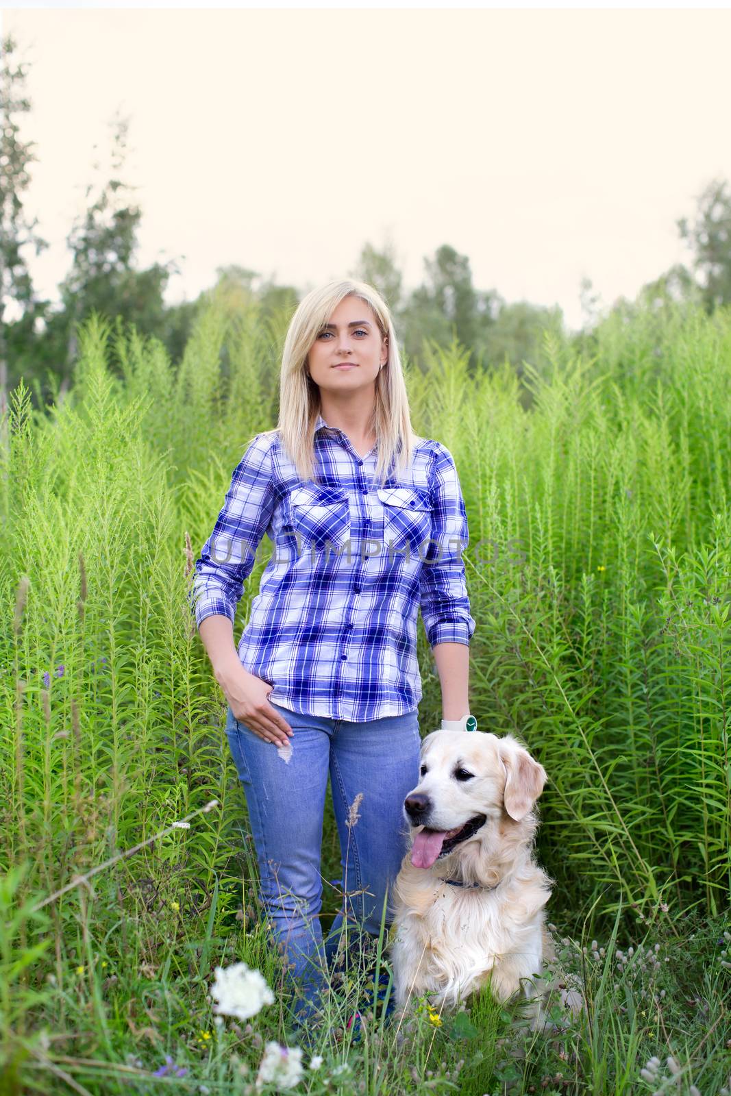 Girl walking with a dog on a green meadow