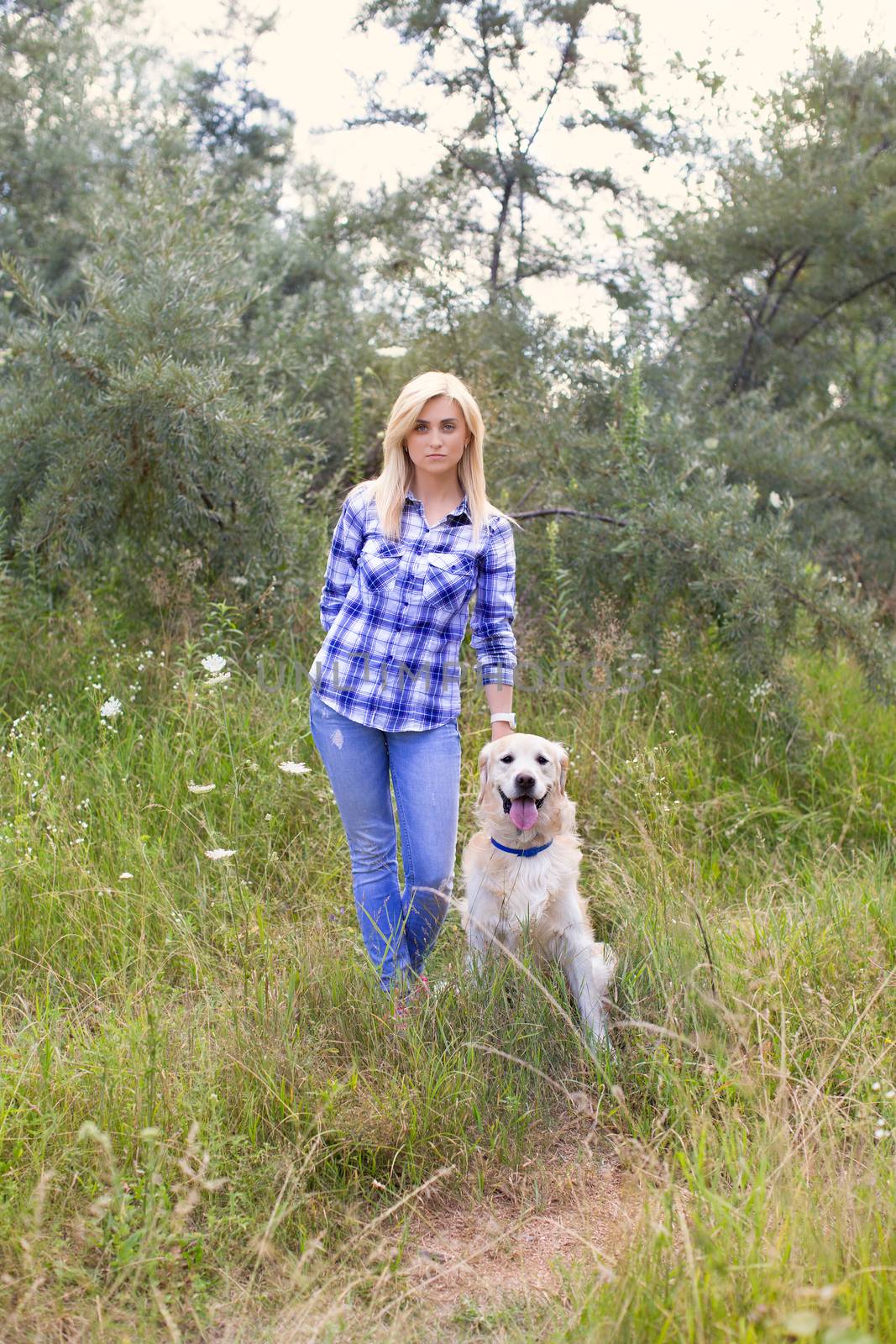 Girl walking with a dog on a green meadow