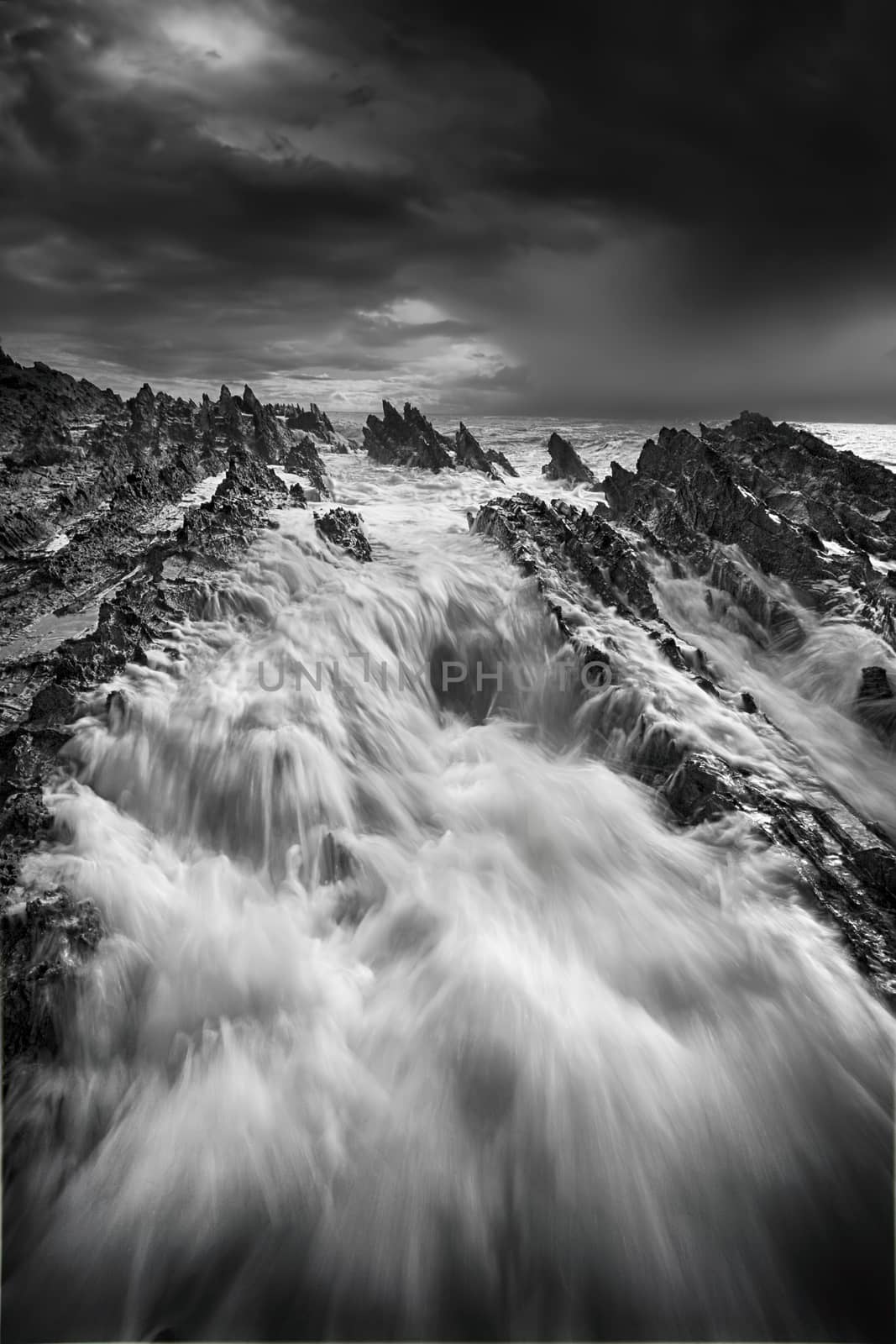 Storm approaching and rough seas with big flows over jagged deathly rocks