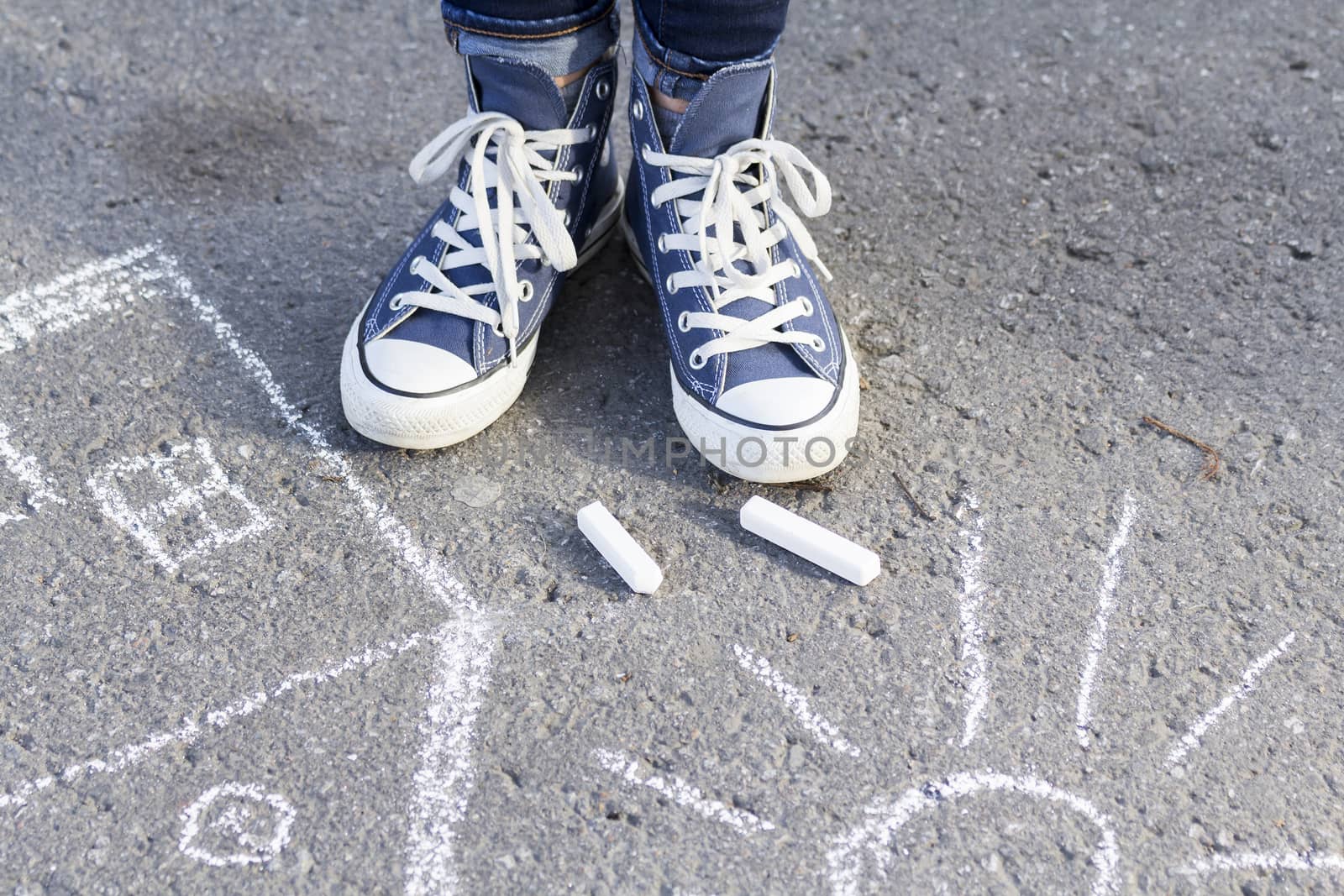 About drawing with chalk on the pavement feet in fashionable sneakers