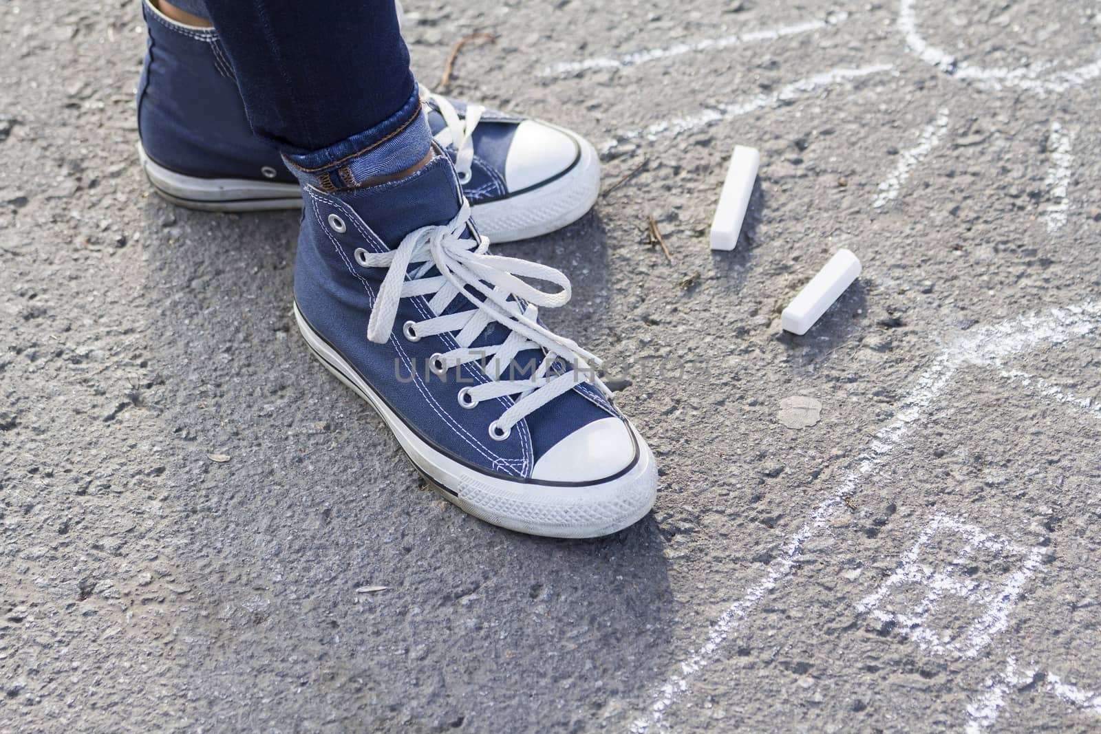 About drawing with chalk on the pavement feet in fashionable sneakers