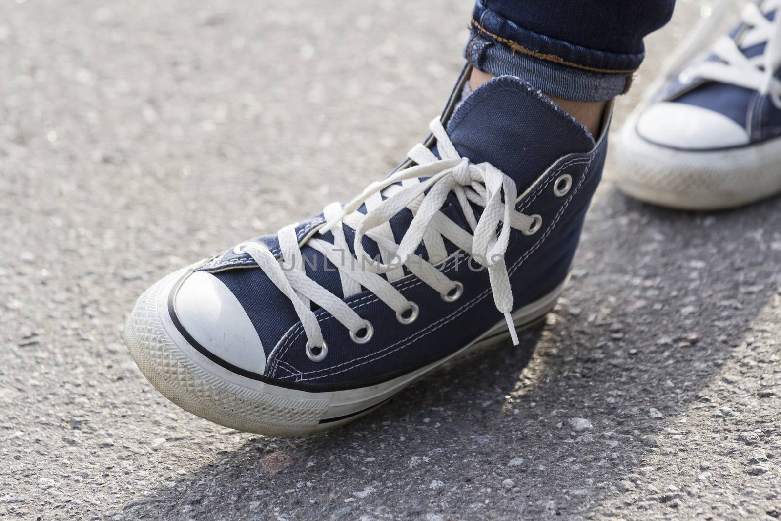 Close-up of female feet in fashionable sneakers are standing on the sidewalk