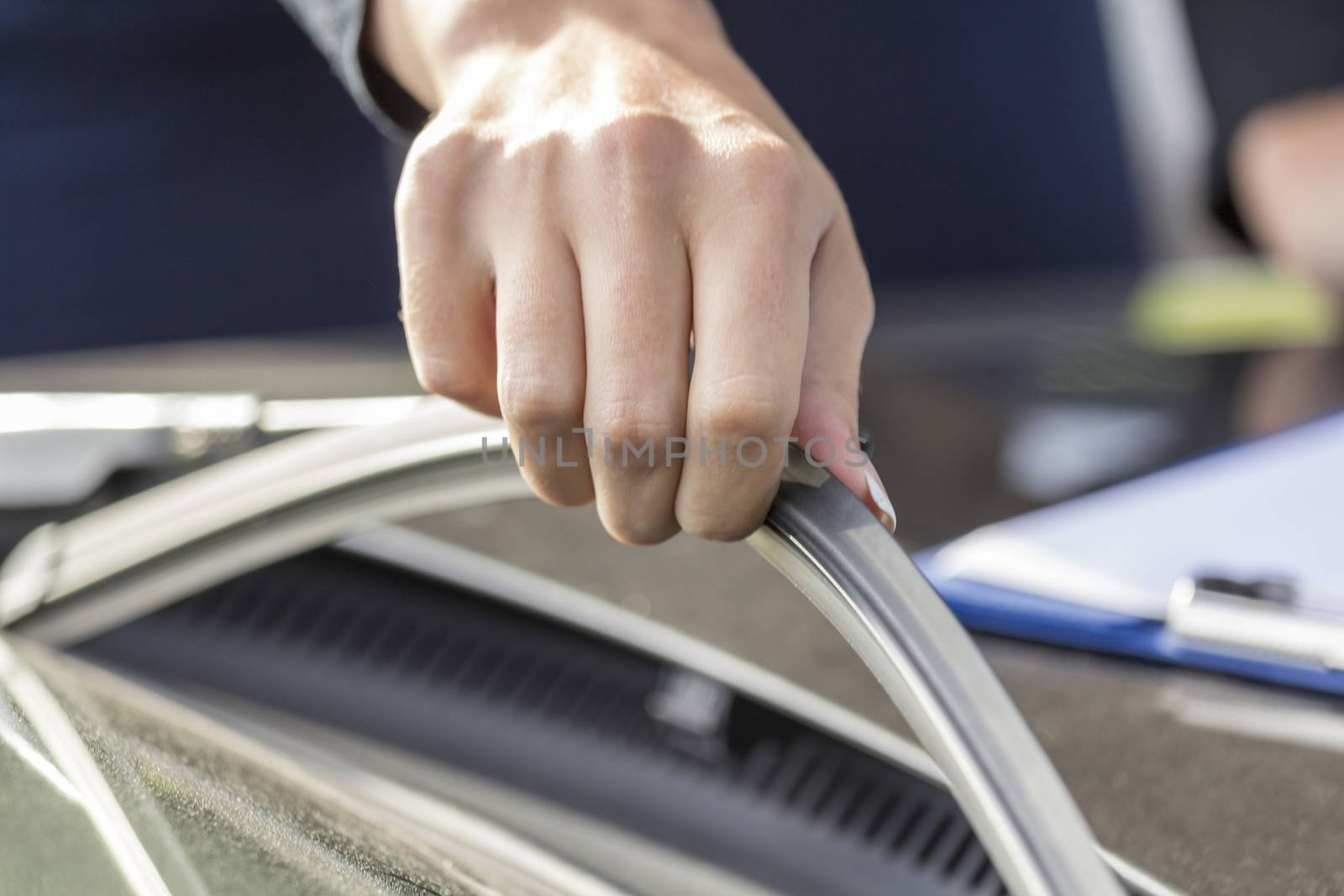 Girls hand regulates and inspects the wipers on the glass of the car