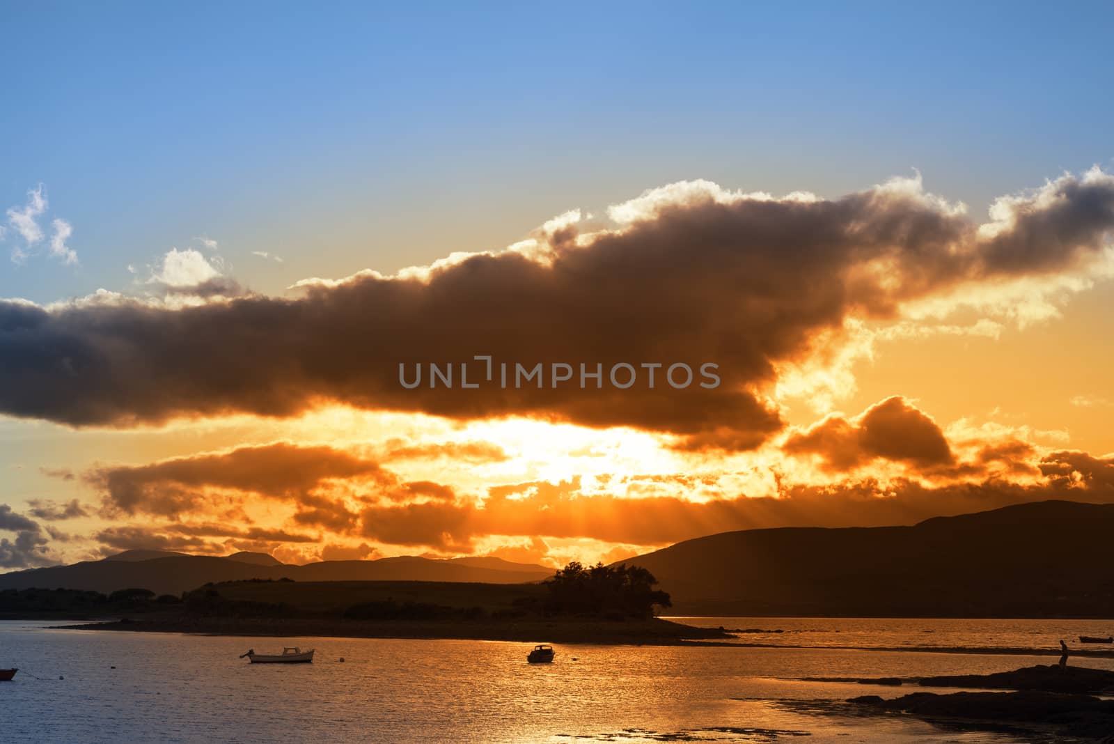 boats in a quiet bay with island near kenmare on the wild atlantic way ireland with an red sunset