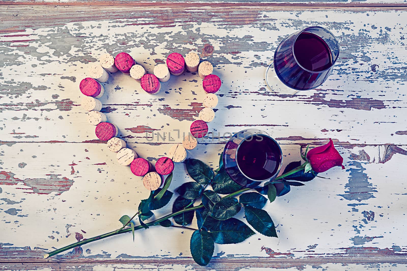 Two glasses of red wine a heart with a cork and a red rose in a vintage style.