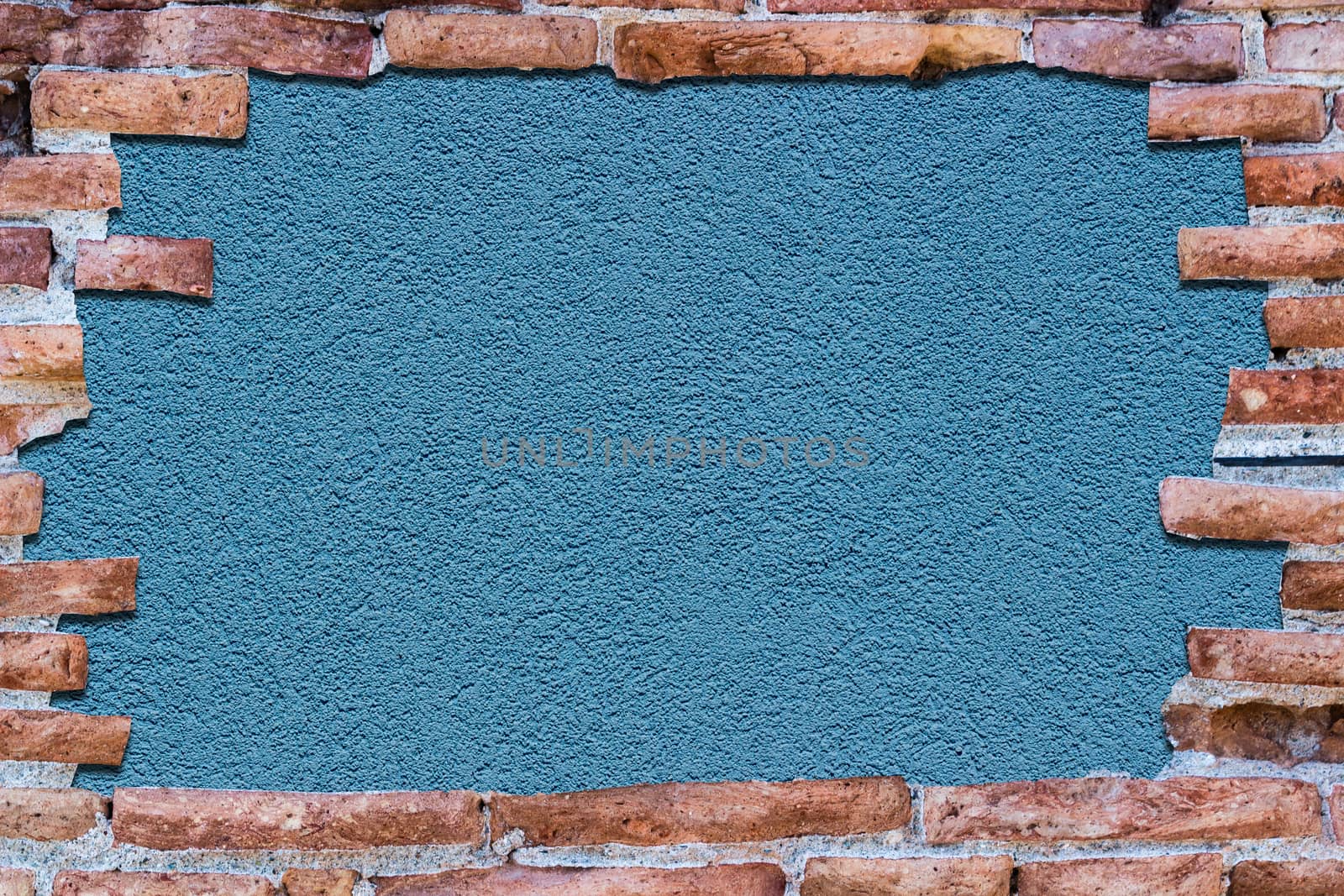 Ancient red brick wall with a hole over a bakground blue.