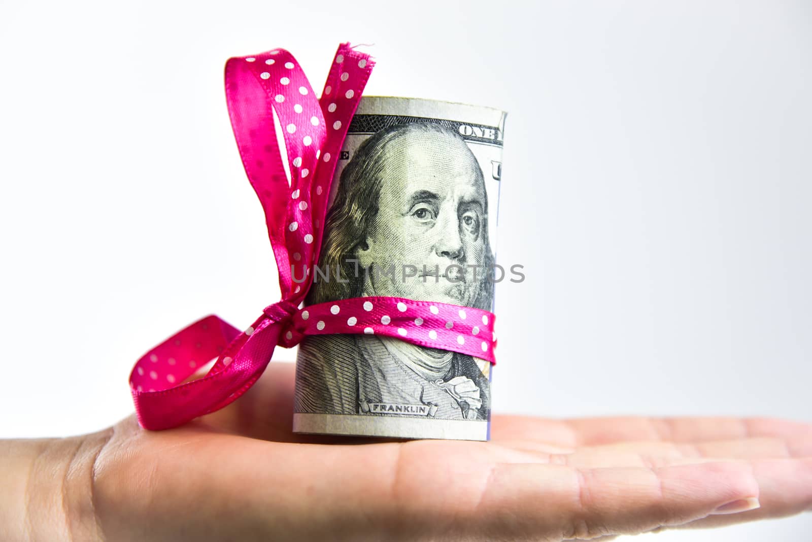 Hand holding bundle of banknotes tied in a bow isolated on white.