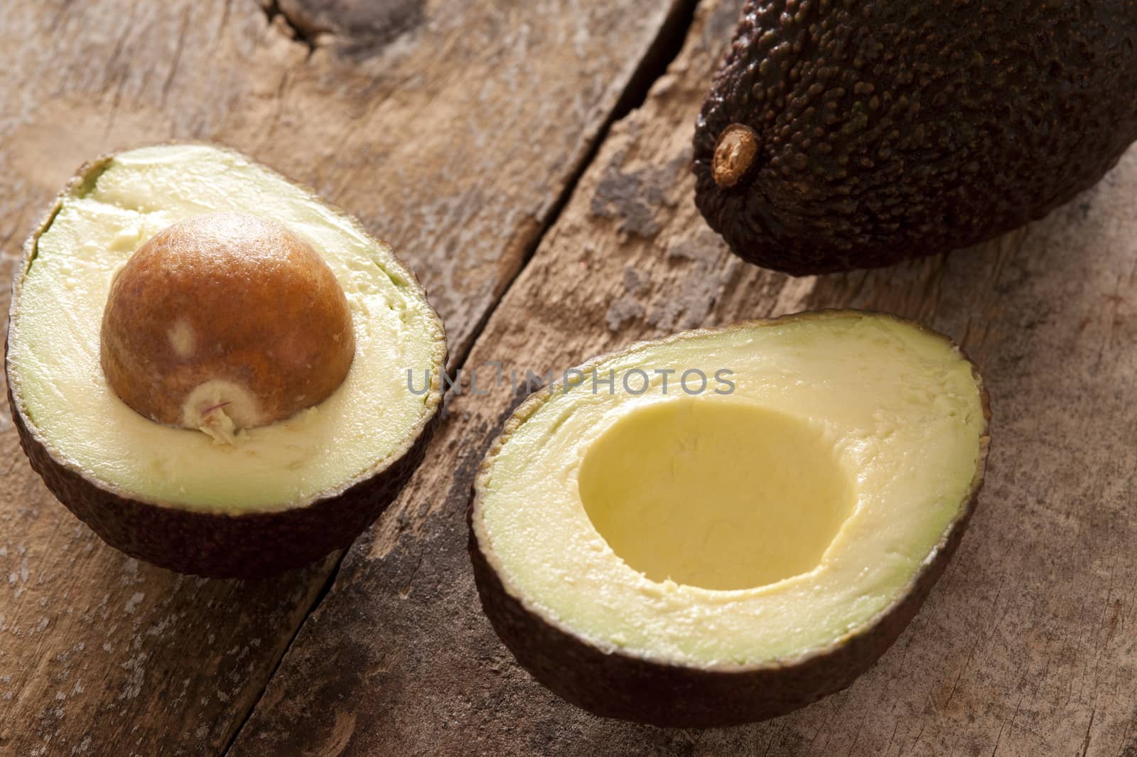 Delicious light green avocado sliced in half and placed on a rustic wooden table