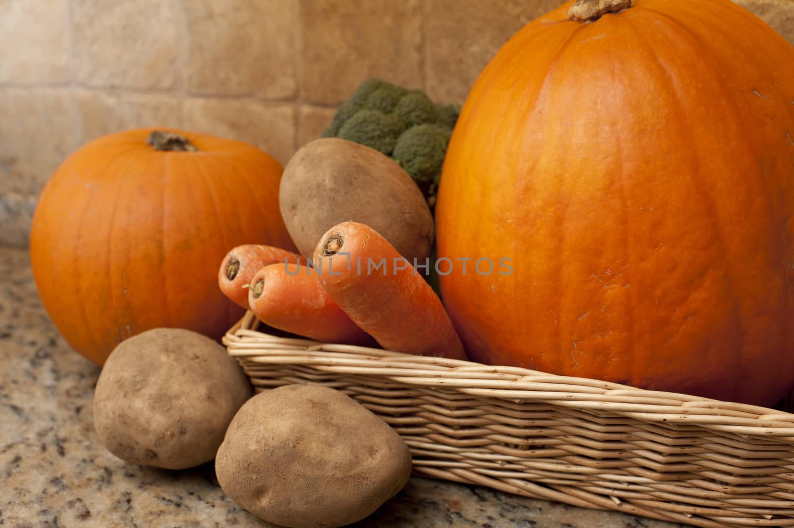 Rectangular wicker basket filled with vegetables such as carrots, potatoes, broccoli and pumpkins