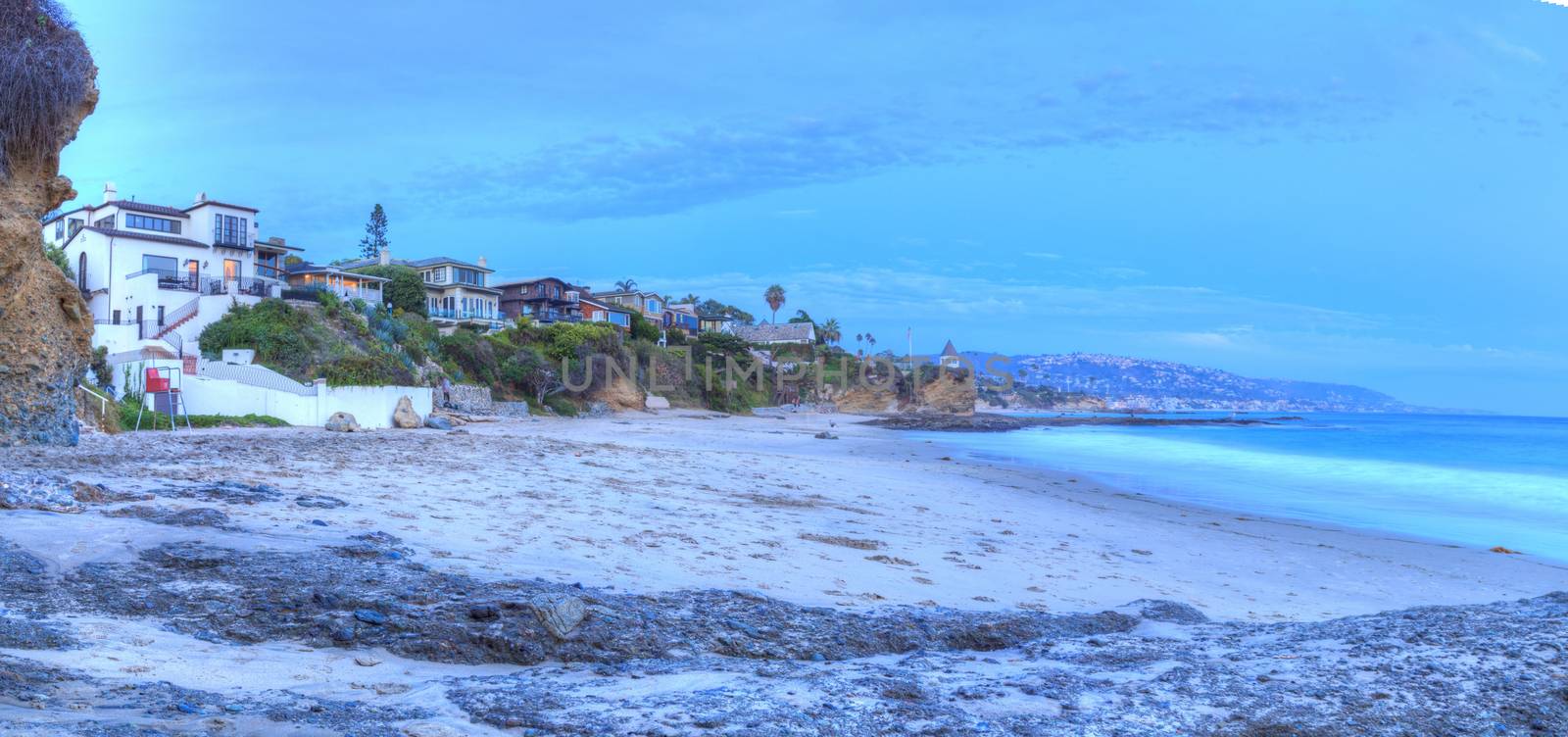 Sunset over the rocks at Shaws Cove in Laguna Beach as water flows over the stone in HDR