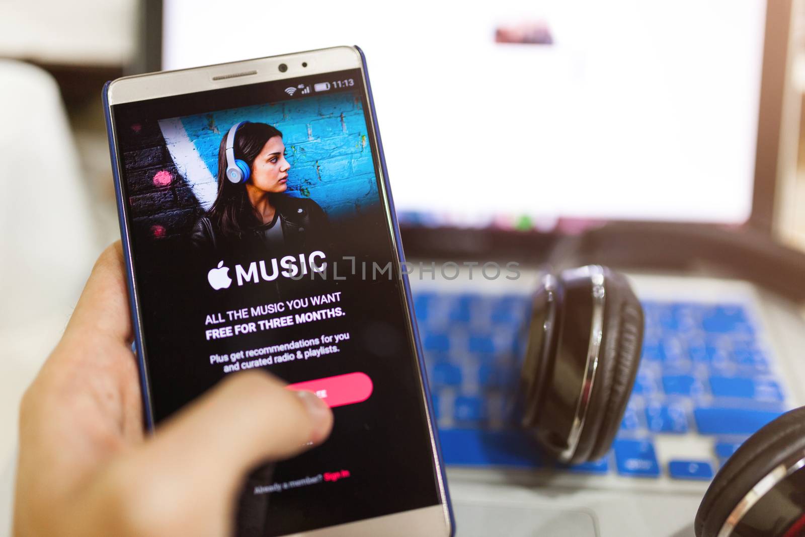 Man hand holding screen shot of Apple music app showing on Andro by nopparats