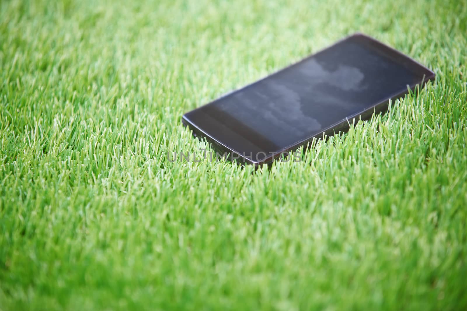 Smartphone lost in the grass. Horizontal photo