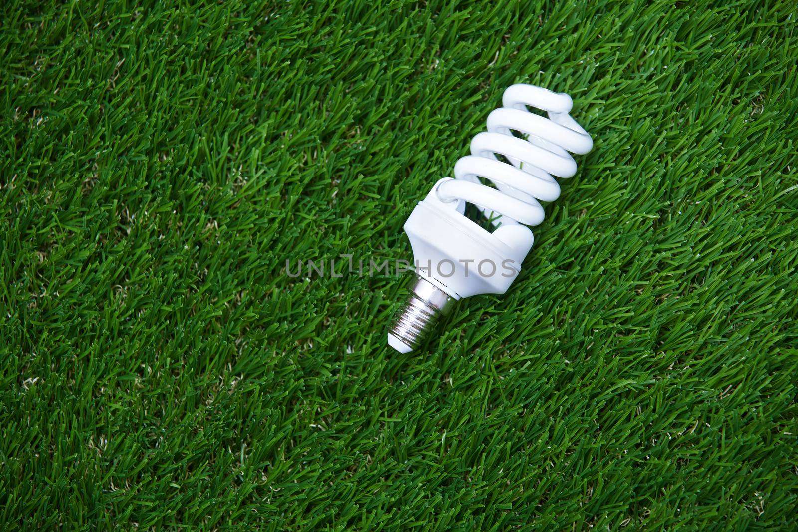 Energy saving bulb in the grass. Horizontal photo