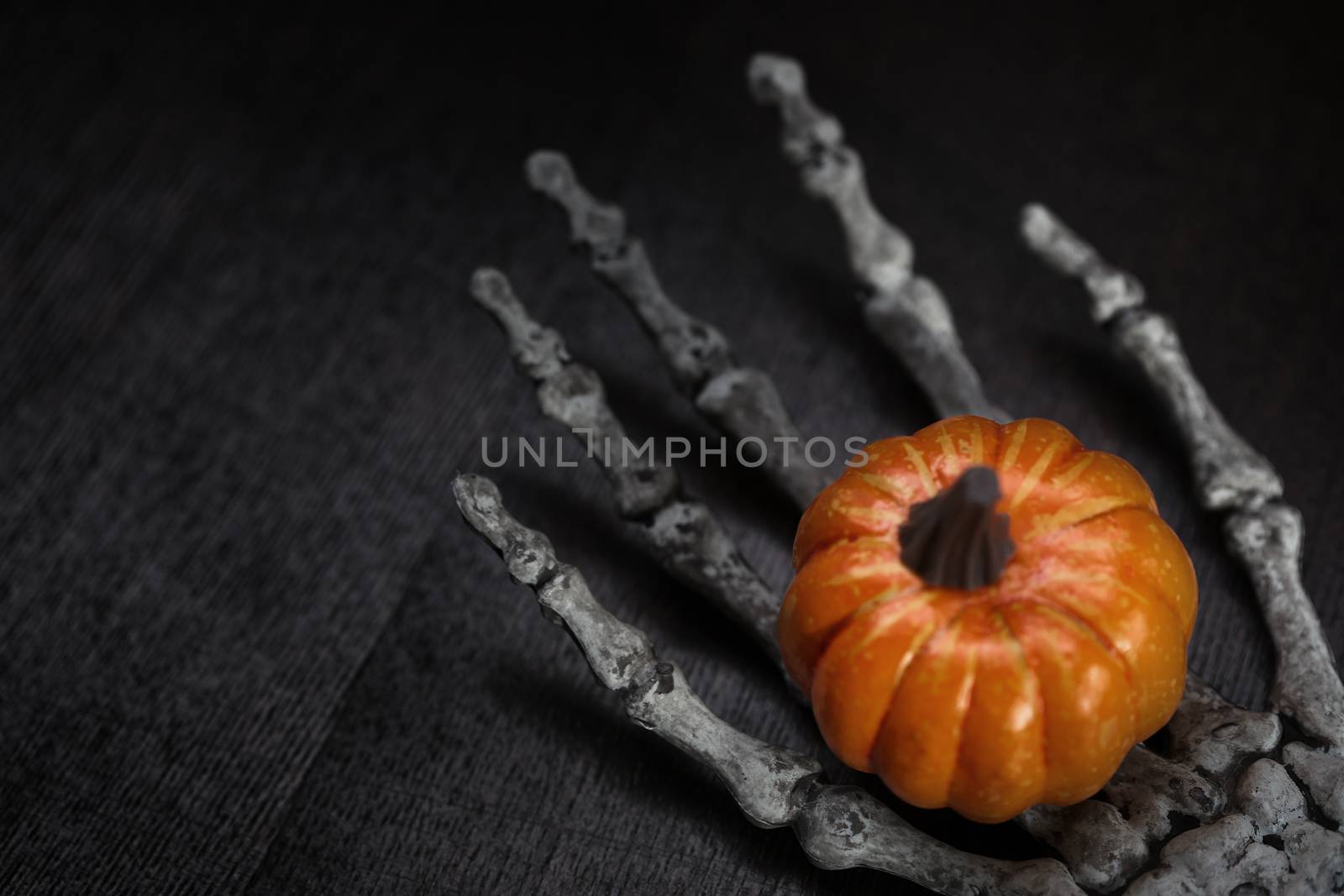 Skeleton hand holding Halloween pumpkin