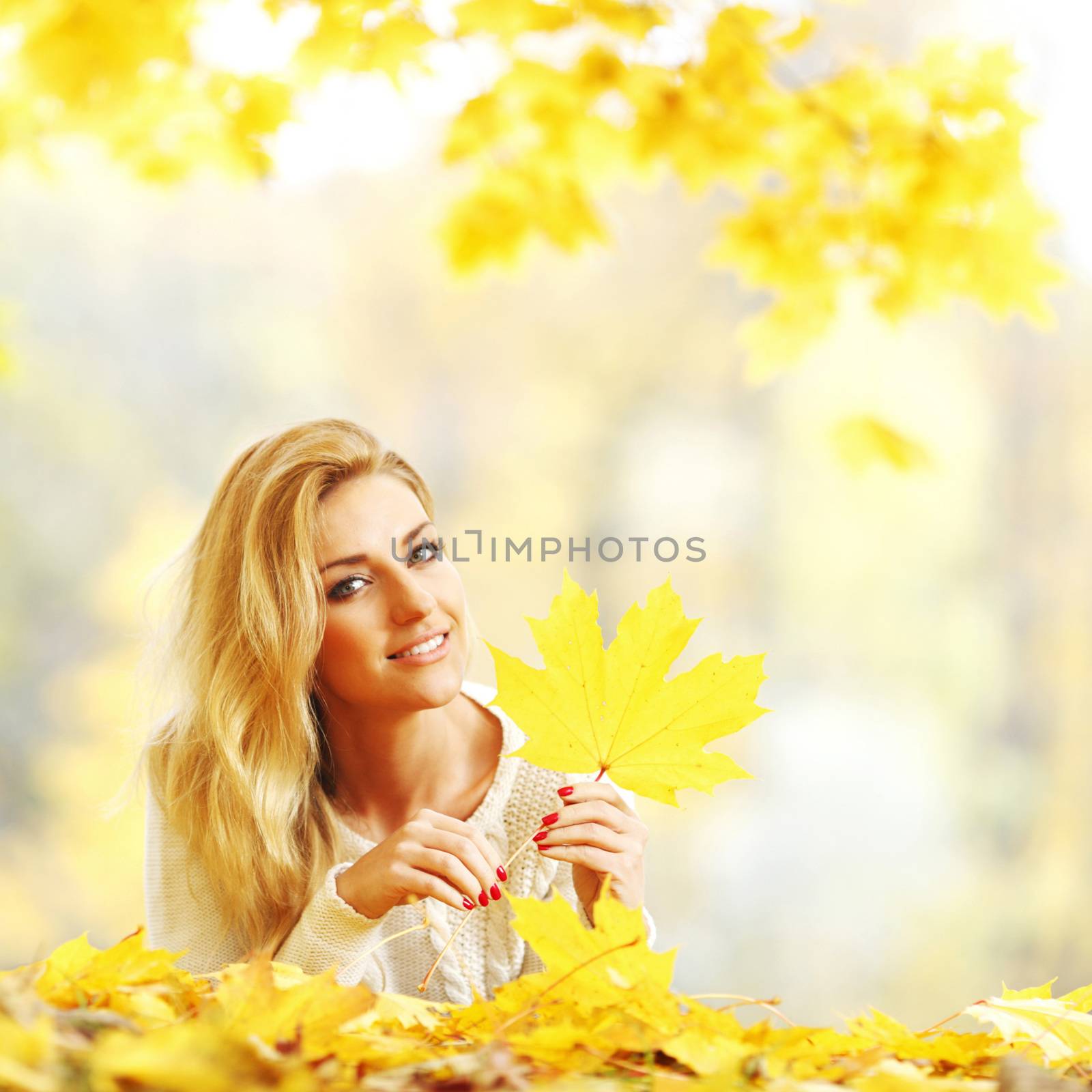Woman laying on autumn leaves by Yellowj