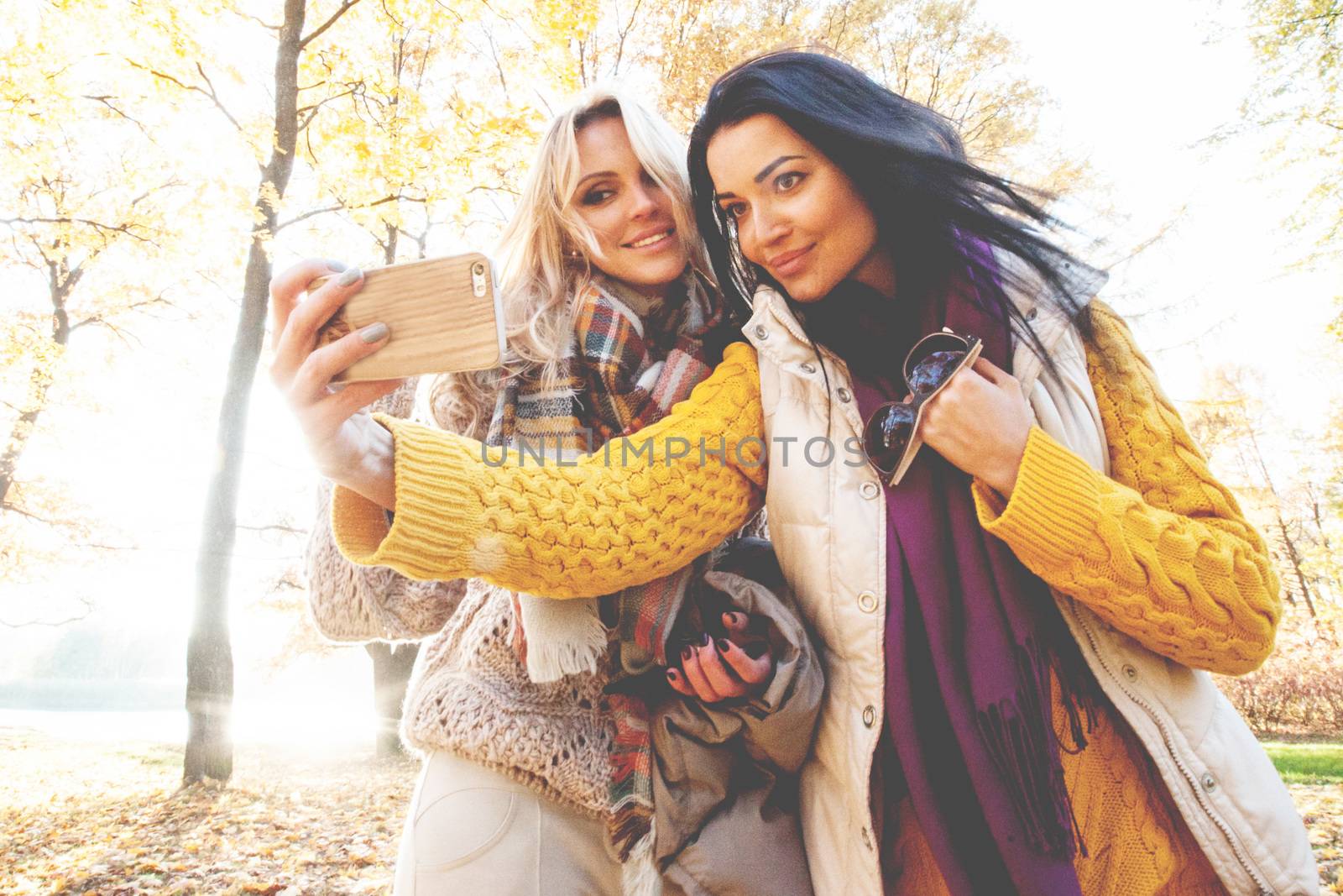 Two happy women taking selfie in autumn park