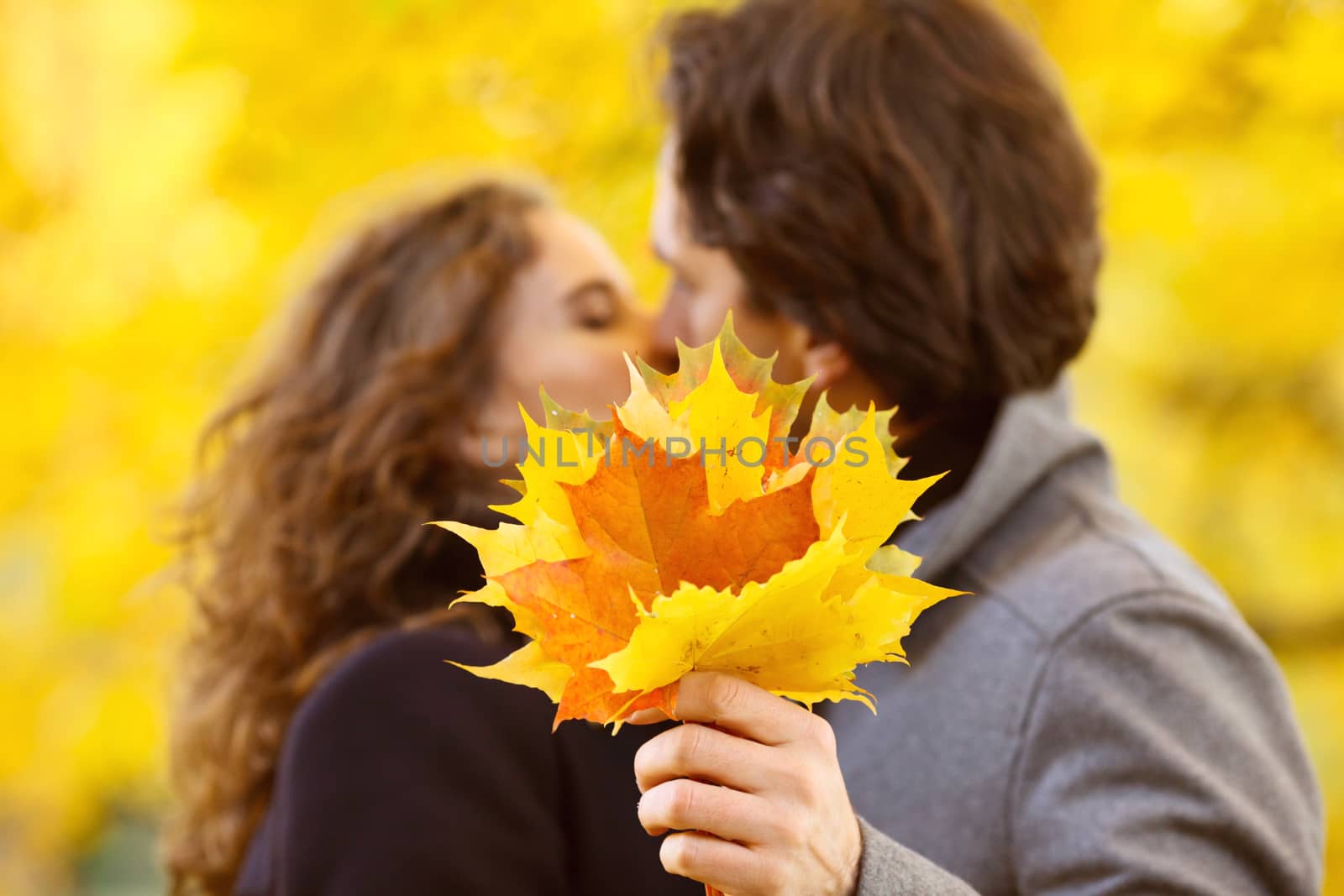 Happy couple kissing in autumn park with yellow trees