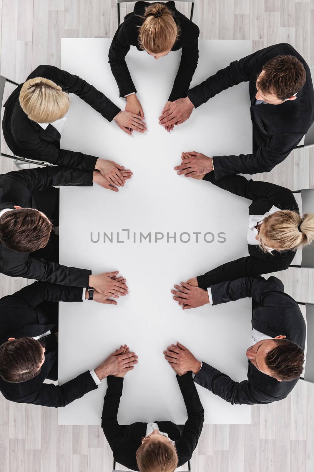 Diverse business people sitting around the table on a meeting and holding hands