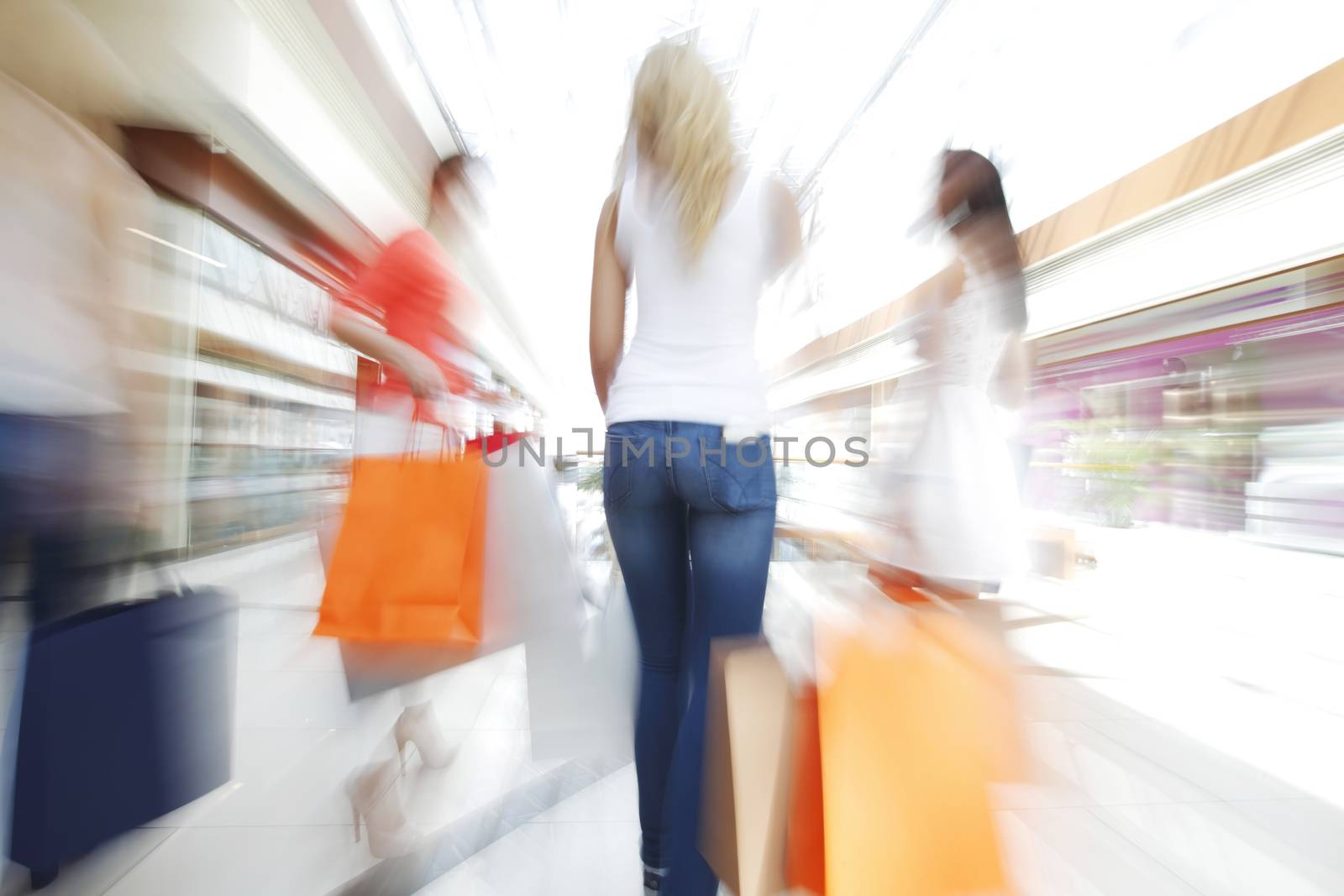 Women walking fast in shopping mall with bags