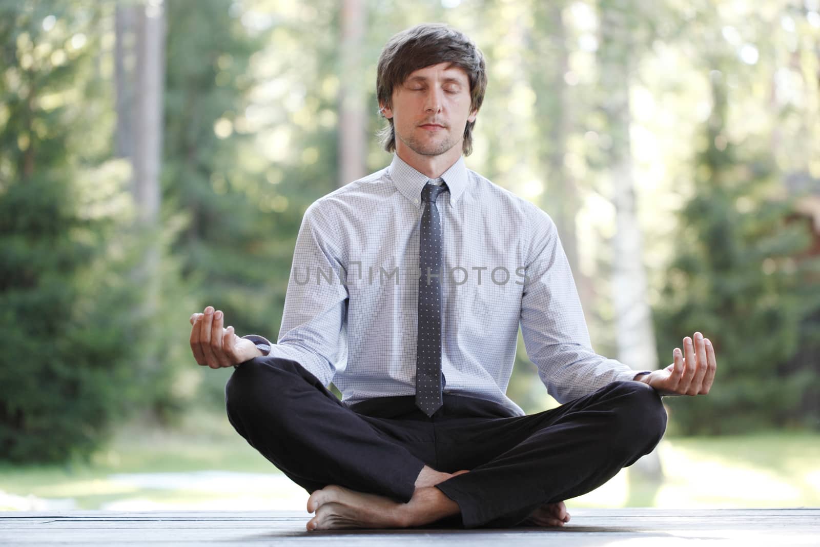 Businessman in suit practicing yoga in park