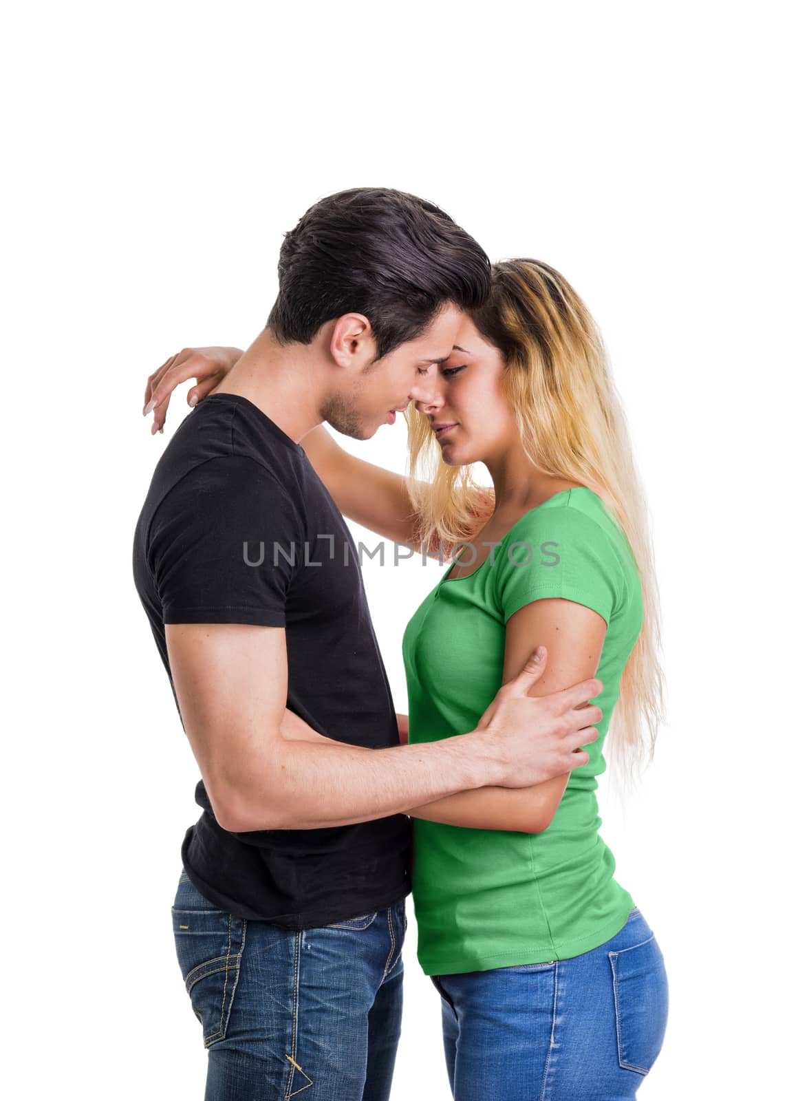 Young couple in love, cuddling, embracing and kissing, studio shot on white background