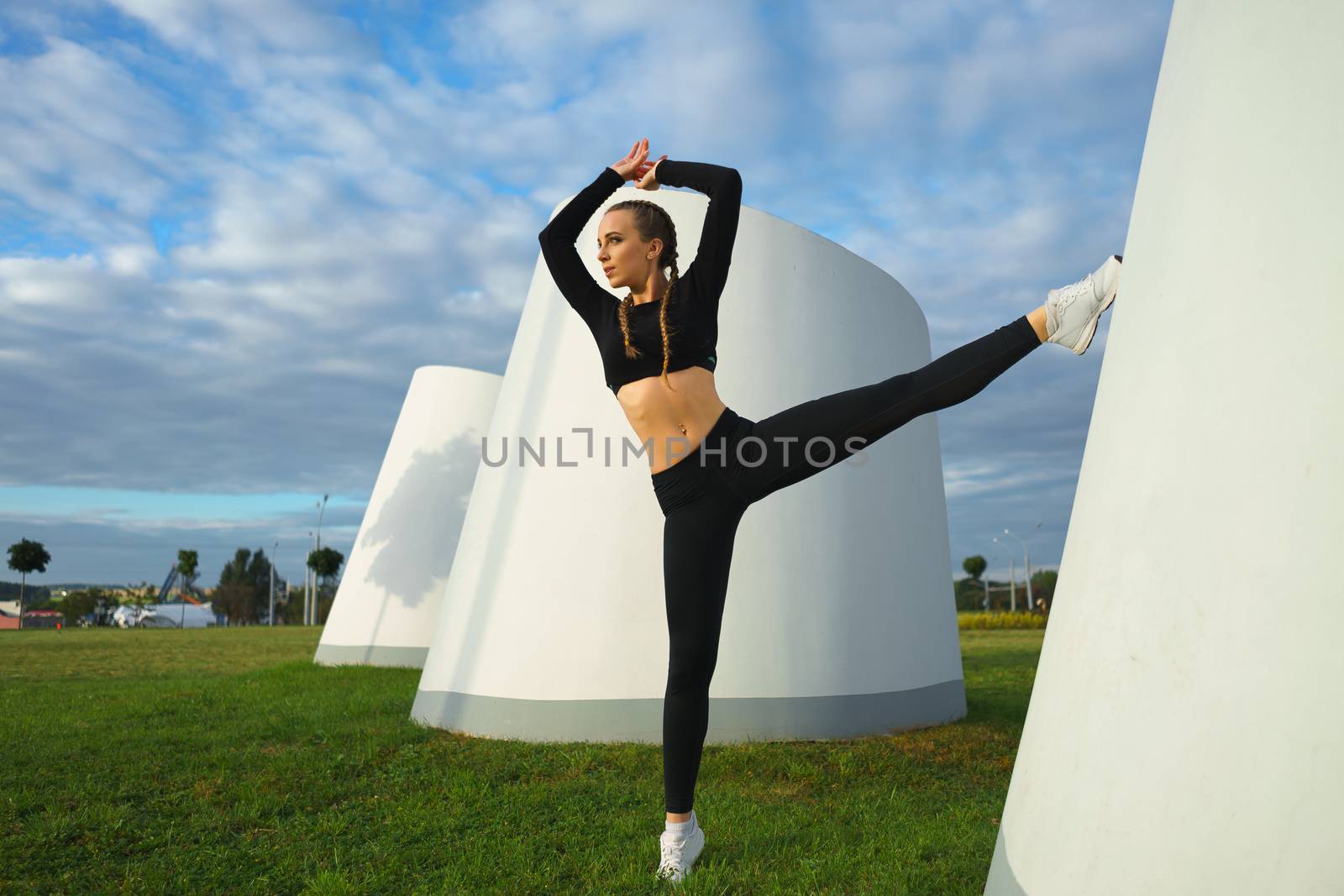 Happy girl stretch outdoor at modern urban area during sunset by mrakor